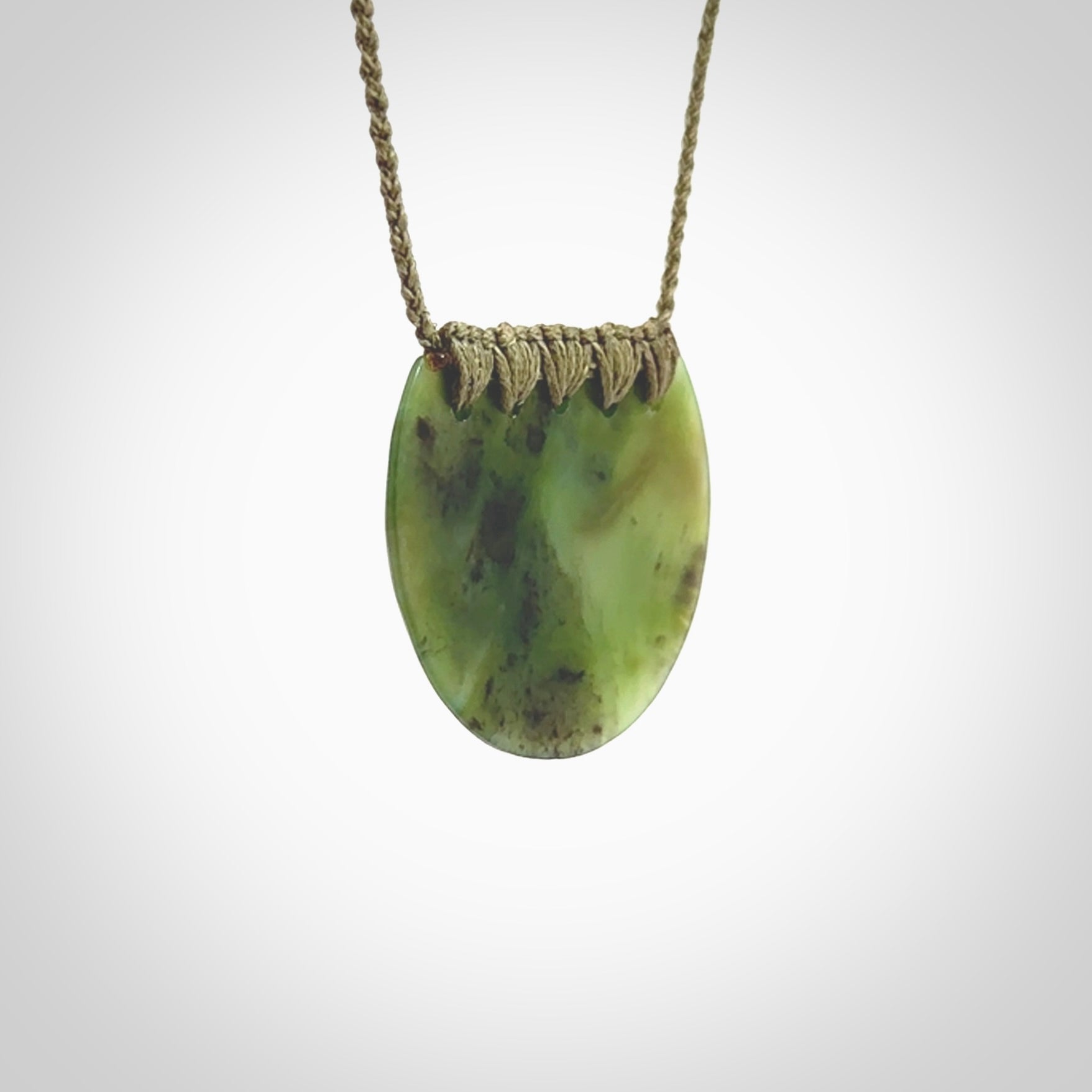 This piece is a disc pendant, hand carved for us by Ric Moor from a lovely milky green piece of New Zealand jade. It is suspended on a olive coloured braided cord that is length adjustable.