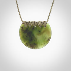 This piece is a disc pendant, hand carved for us by Ric Moor from a lovely milky green piece of New Zealand jade. It is suspended on a olive coloured braided cord that is length adjustable.