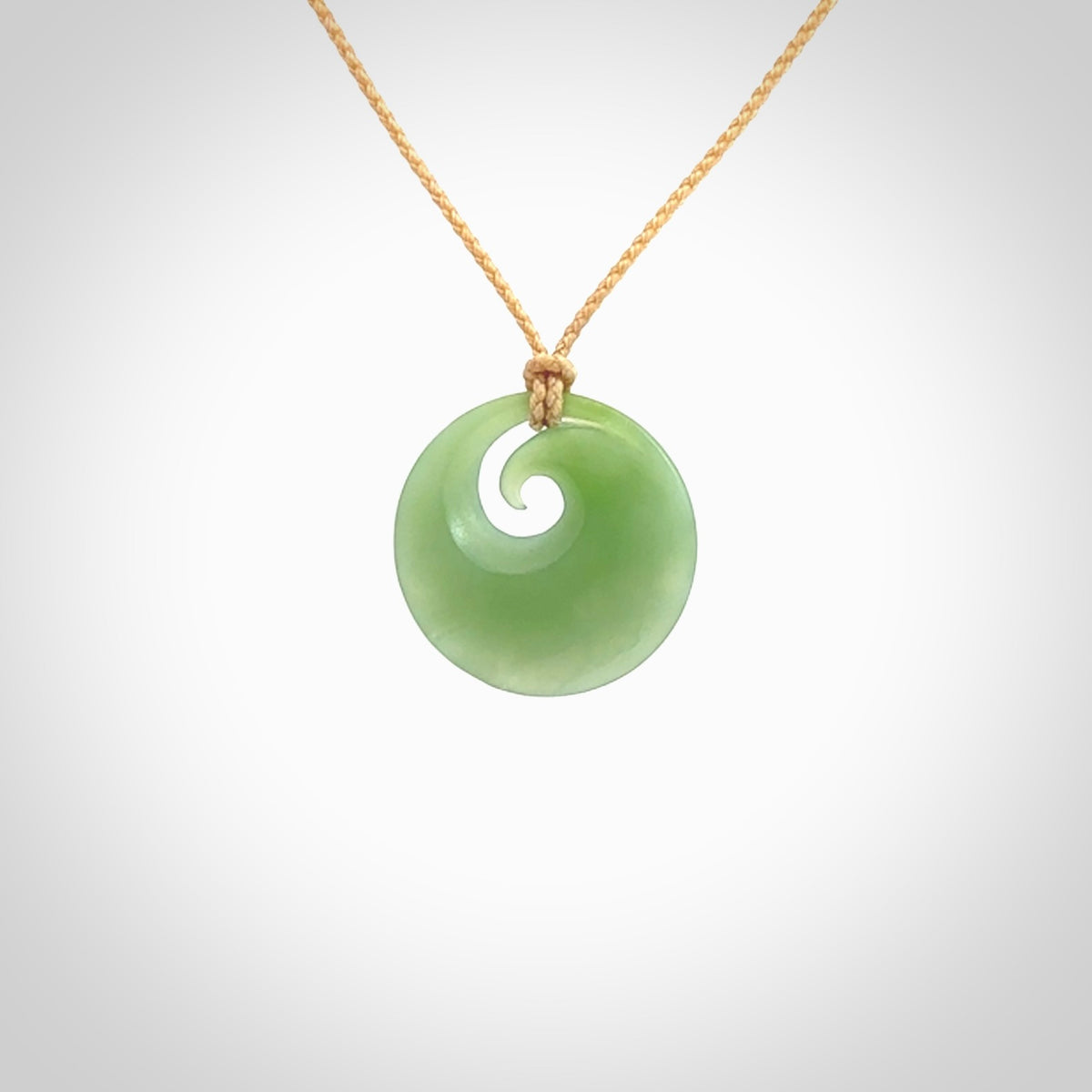 This is a small light green New Zealand Inanga jade koru pendant. We have bound this with a fine beige coloured cord necklace. The necklace is adjustable so you can position the piece where it suits you the best. Hand made by Ric Moor.