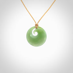 This is a small light green New Zealand Inanga jade koru pendant. We have bound this with a fine beige coloured cord necklace. The necklace is adjustable so you can position the piece where it suits you the best. Hand made by Ric Moor.