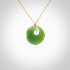 This is a small light green New Zealand Inanga jade koru pendant. We have bound this with a fine beige coloured cord necklace. The necklace is adjustable so you can position the piece where it suits you the best.