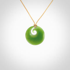 This is a small light green New Zealand Inanga jade koru pendant. We have bound this with a fine beige coloured cord necklace. The necklace is adjustable so you can position the piece where it suits you the best.