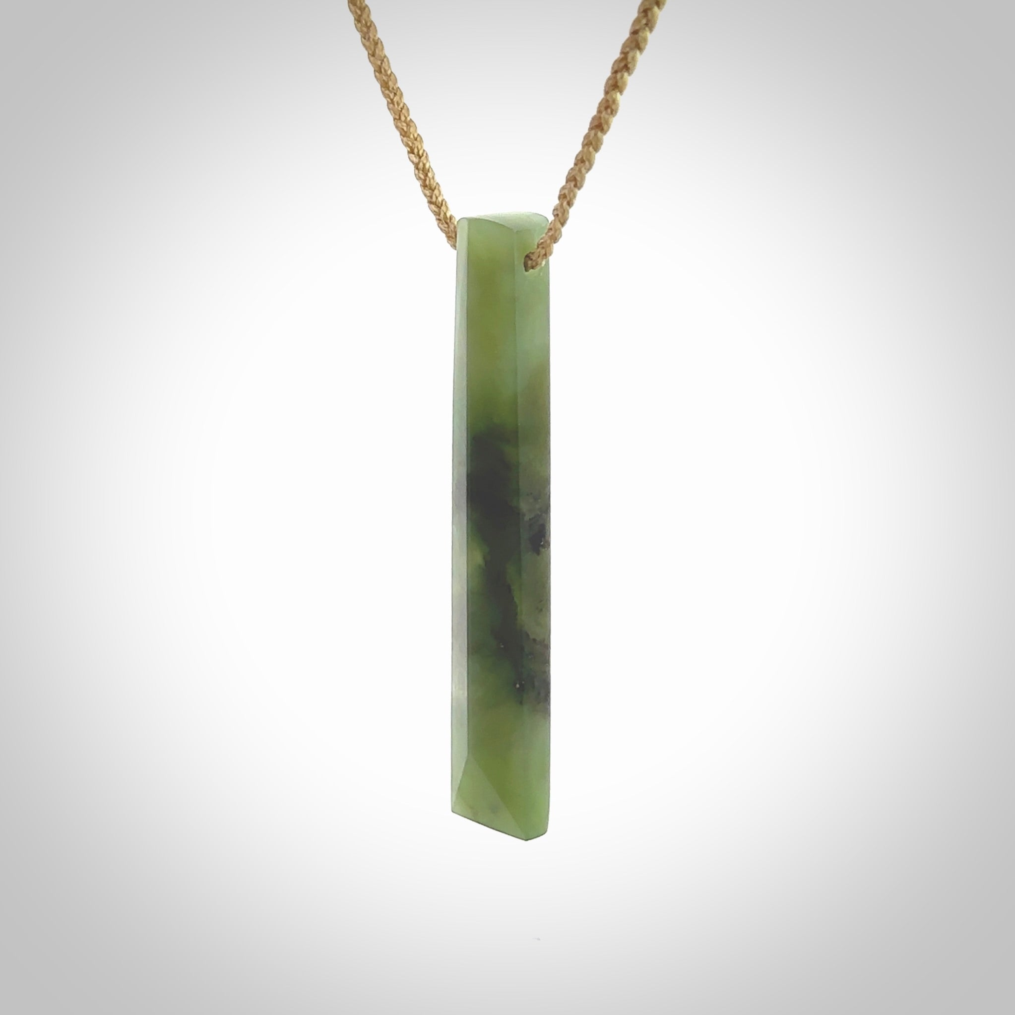 This photo shows a large Totoweka jade drop shaped pendant. It a a lovely, semi-translucent jade. The cord is tan and is adjustable in length. One only large, contemporary drop necklace from New Zealand Totoweka Jade, by Rueben Tipene.