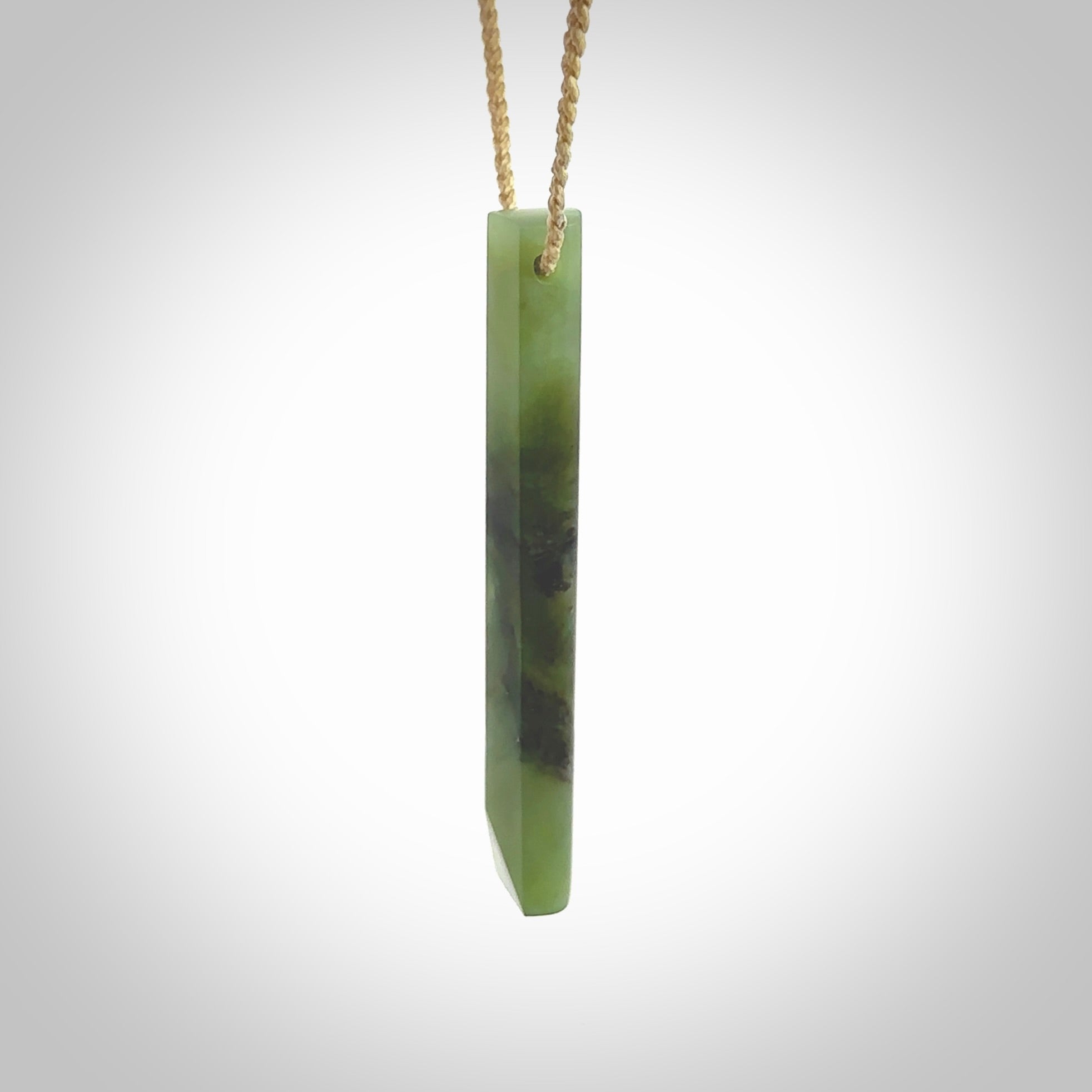 This photo shows a large Totoweka jade drop shaped pendant. It a a lovely, semi-translucent jade. The cord is tan and is adjustable in length. One only large, contemporary drop necklace from New Zealand Totoweka Jade, by Rueben Tipene.