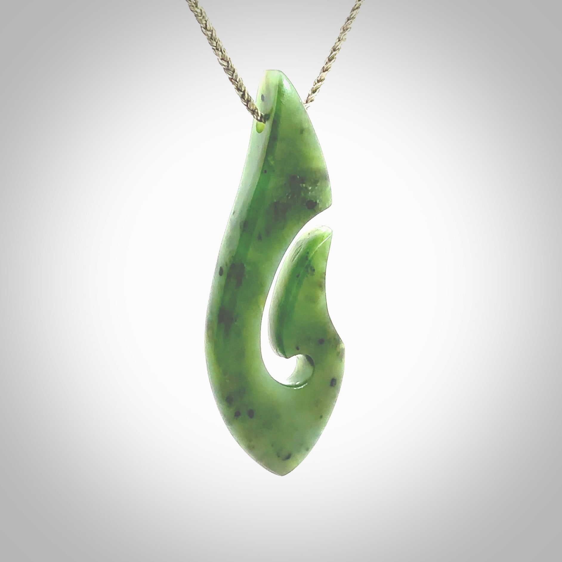 A hand carved hook design pendant, carved in New Zealand Kawakawa Jade. The colour is a beautiful deep green. The cord is khaki green and is length adjustable. Hand made by Rueben Tipene. Delivered with Express courier in a woven kete pouch.