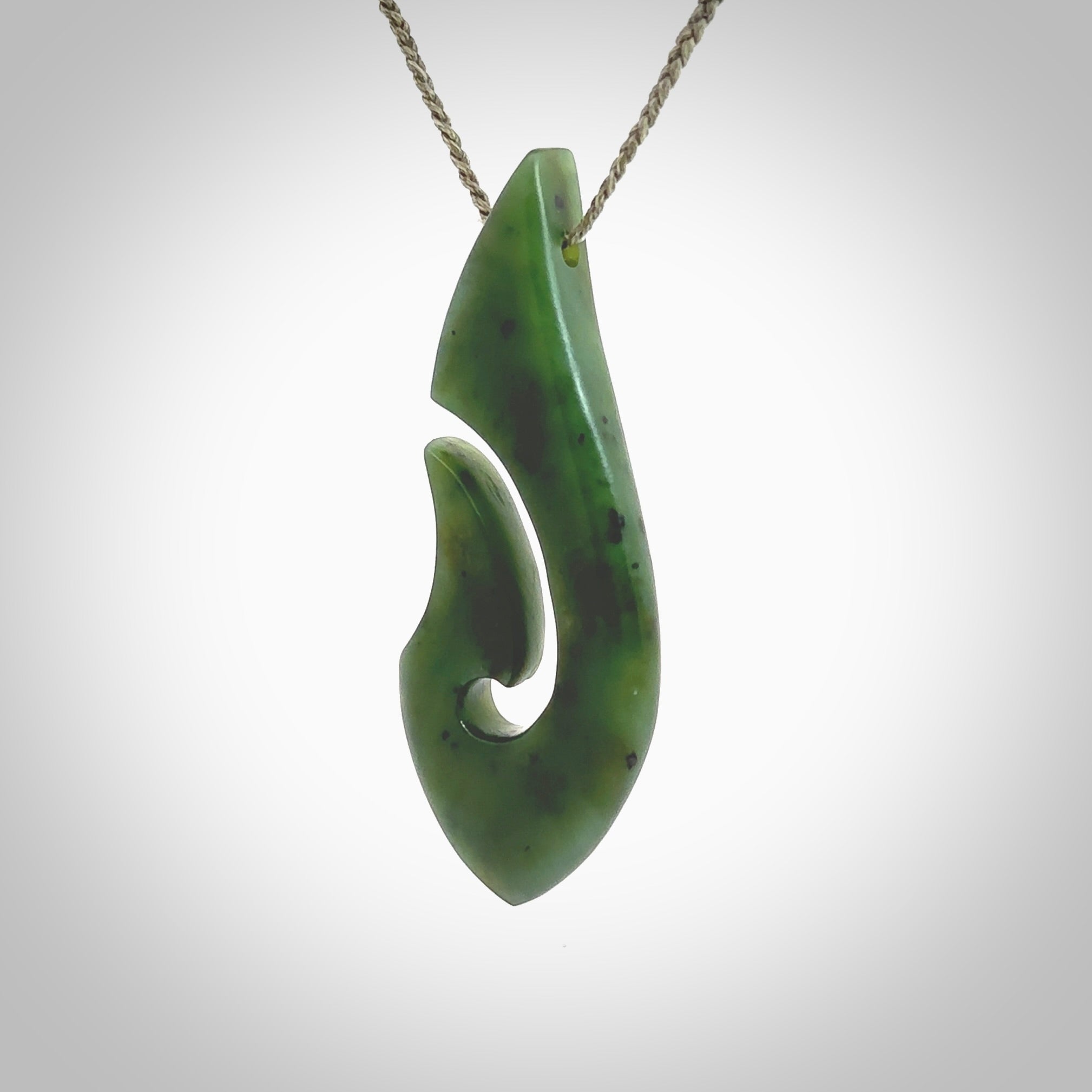 A hand carved hook design pendant, carved in New Zealand Kawakawa Jade. The colour is a beautiful deep green. The cord is khaki green and is length adjustable. Hand made by Rueben Tipene. Delivered with Express courier in a woven kete pouch.