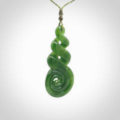 Ross Crump triple twist with koru pendant. Hand carved from rare New Zealand jade this is a beautiful pounamu pendant. The cord is 4-plait in a grass green and khaki colour and is length adjustable. It has a floret in khaki green. It is a delicate and very beautiful greenstone pendant. For sale online by NZ Pacific.