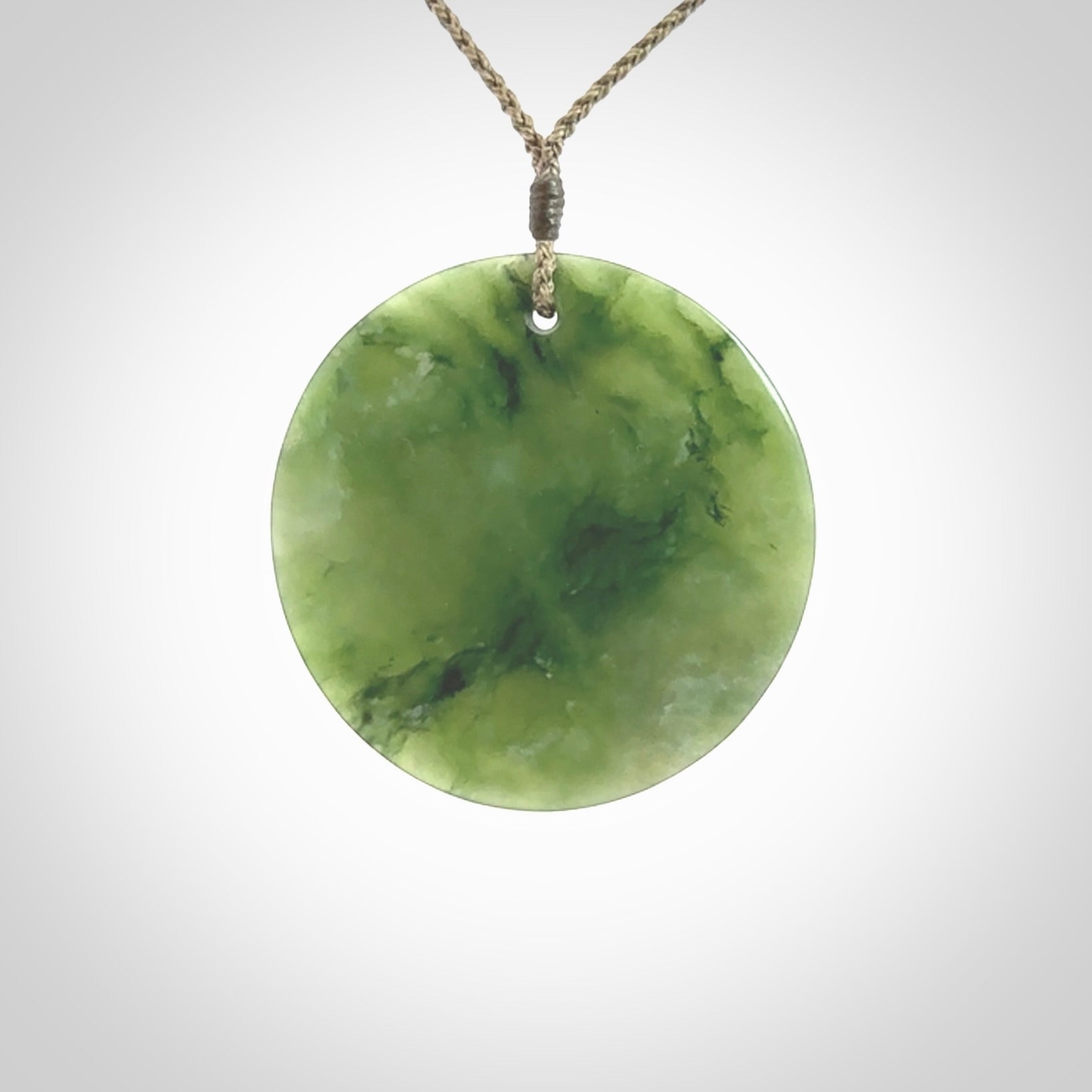 Hand carved New Zealand Jade disc pendant by Ric Moor. Provided with khaki adjustable cord. Free worldwide delivery. One only pendant.