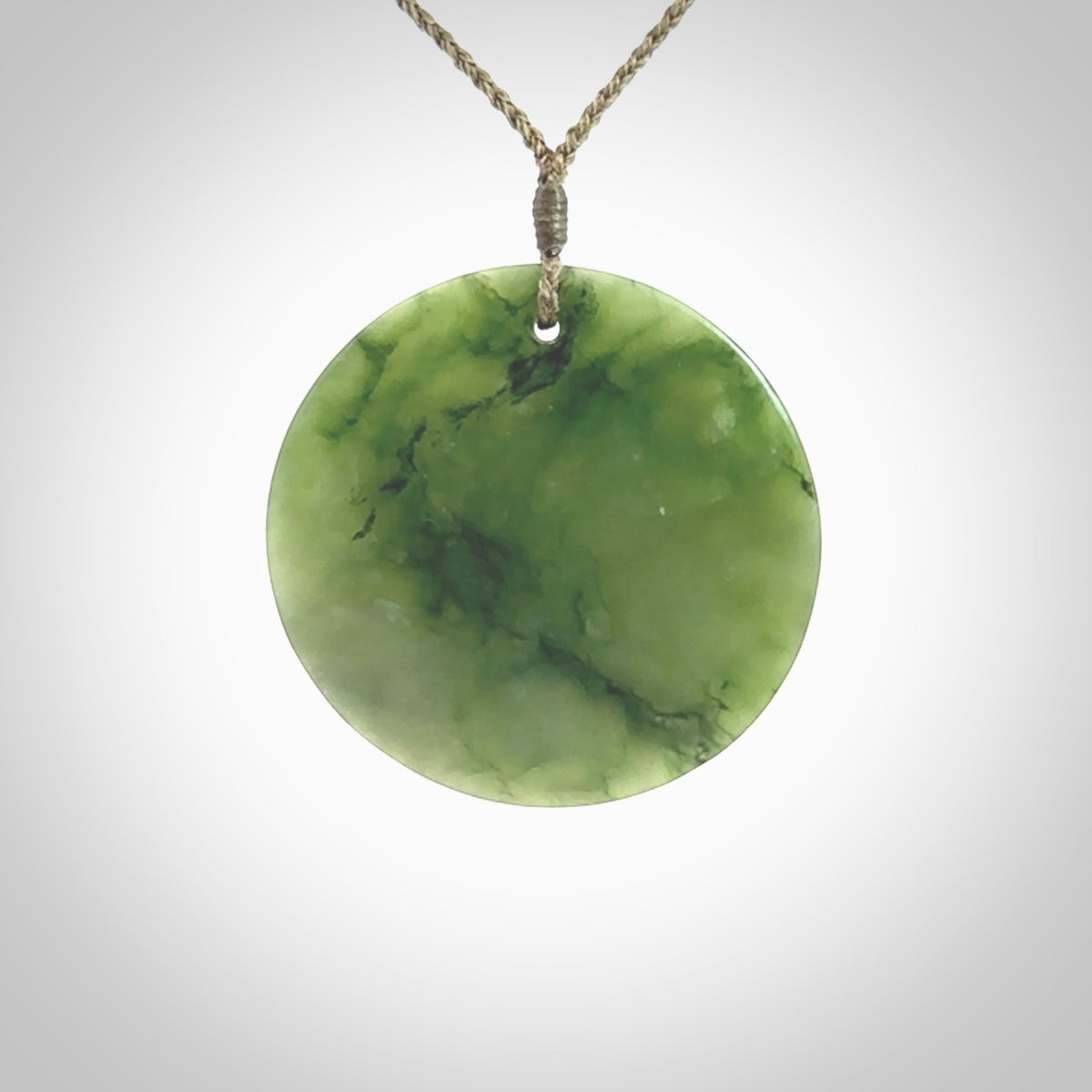 Hand carved New Zealand Jade disc pendant by Ric Moor. Provided with khaki adjustable cord. Free worldwide delivery. One only pendant.