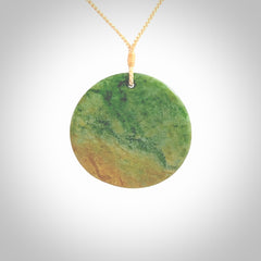 This piece is a large oval round, disc pendant. It was carved for us by Ric Moor from a lovely orange and green piece of New Zealand flower jade. It is suspended on a beige coloured braided cord that is length adjustable.