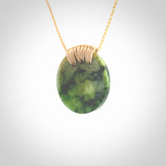 This piece is a medium sized cupped disc pendant. It was carved for us by Ric Moor from a lovely deep and milky green piece of New Zealand flower jade. It is suspended on a beige coloured braided cord that is length adjustable.