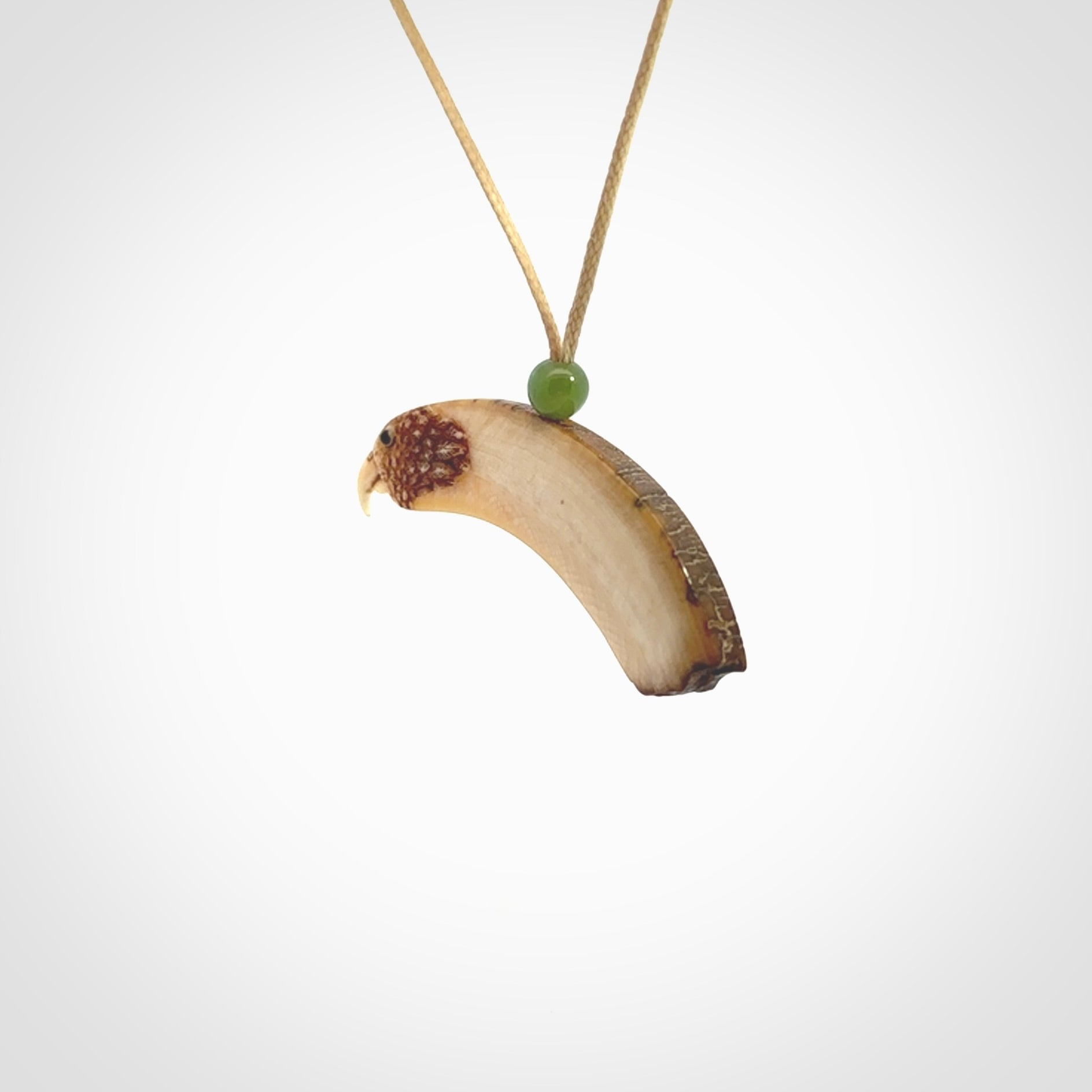 This is a hand carved deer antler bone kea bird head pendant. It is made from deer antler with jade bead. This is a medium sized necklace and is a very unique, one only, pendant that is a collectors piece. Hand carved by New Zealand artist, Sami. Provided with adjustable tan cord.