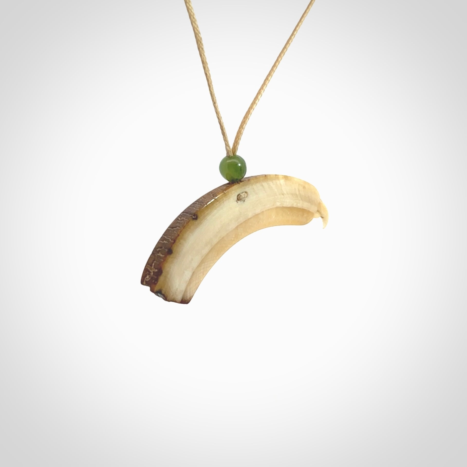 This is a hand carved deer antler bone kea bird head pendant. It is made from deer antler with jade bead. This is a medium sized necklace and is a very unique, one only, pendant that is a collectors piece. Hand carved by New Zealand artist, Sami. Provided with adjustable tan cord.