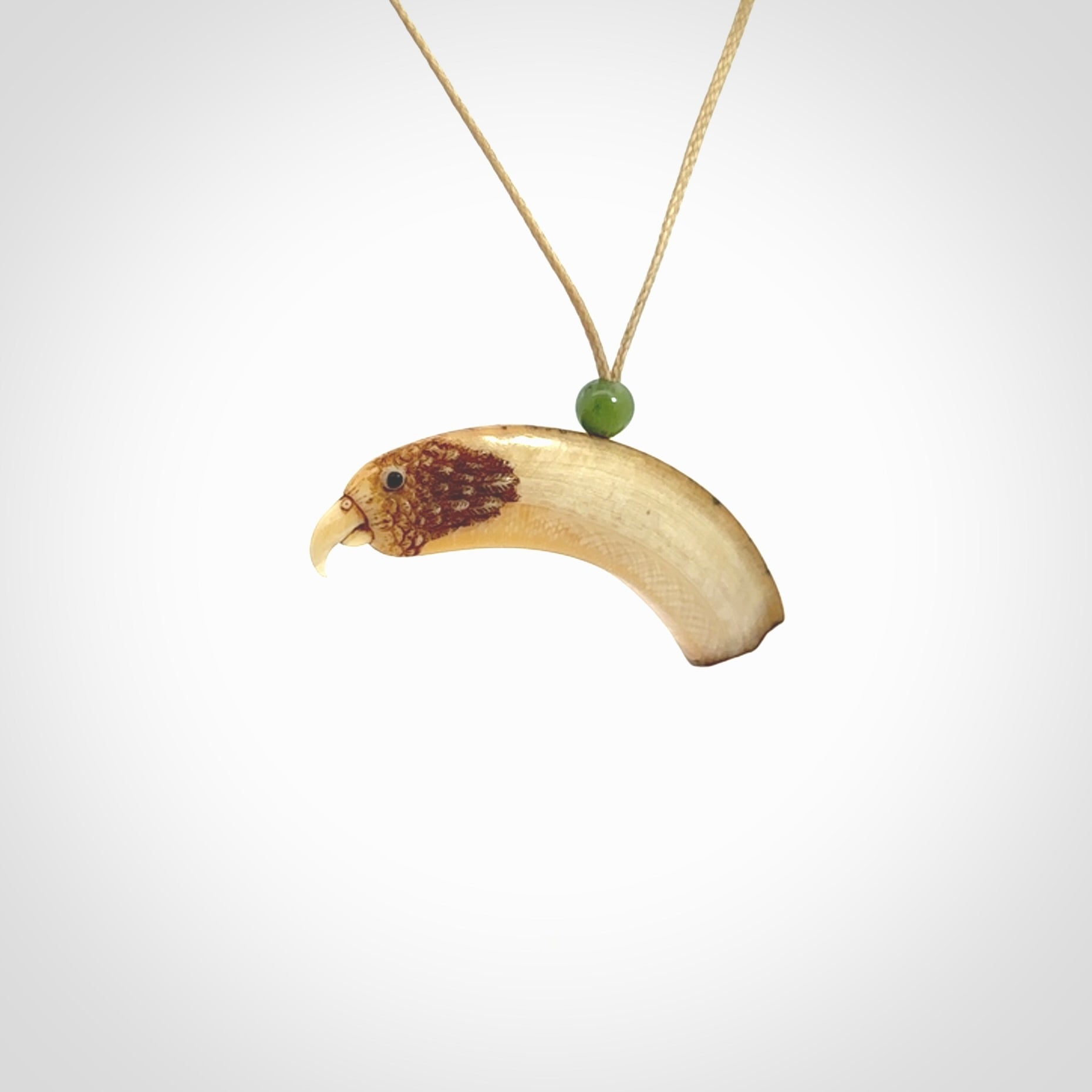 This is a hand carved deer antler bone kea bird head pendant. It is made from deer antler with jade bead. This is a medium sized necklace and is a very unique, one only, pendant that is a collectors piece. Hand carved by New Zealand artist, Sami. Provided with adjustable tan cord.