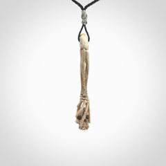 This picture shows a large sized Deer Antler Bone skull in skeleton hand pendant that we have hand carved. It is polished to a soft shine and is a very striking piece. The cord is a black colour and has a small grey floret binding just above the pendant.