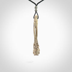 This picture shows a large sized Deer Antler Bone skull in skeleton hand pendant that we have hand carved. It is polished to a soft shine and is a very striking piece. The cord is a black colour and has a small grey floret binding just above the pendant.