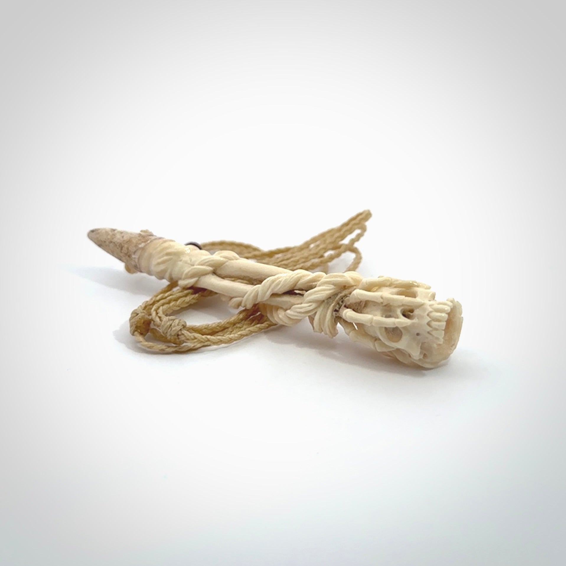 This picture shows a large sized Deer Antler Bone skull in skeleton hand pendant that we have hand carved. It is polished to a soft shine and is a very striking piece. The cord is a oat colour and has a small burgundy floret binding just above the pendant.