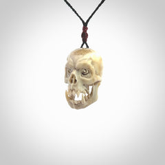 This picture shows a medium sized Deer Antler Bone skull pendant that we have hand carved. It is polished to a soft shine and is a very striking piece. The cord is a black colour and has a small burgundy floret binding just above the pendant.