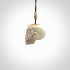 This picture shows a medium sized Deer Antler Bone monster skull pendant that we have hand carved. It is polished to a soft shine and is a very striking piece. The cord is a wapiti brown colour and has a small oat floret binding just above the pendant.