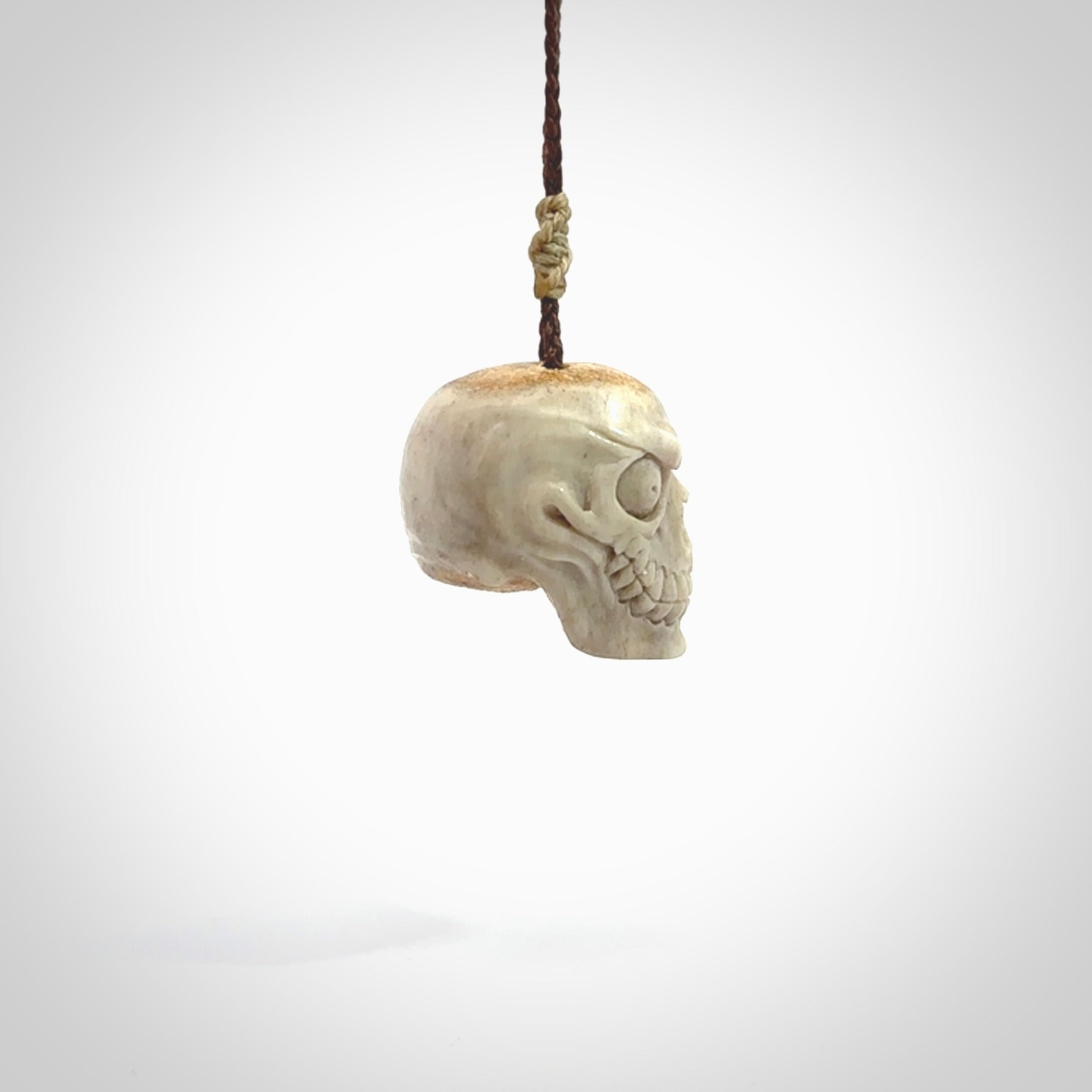 This picture shows a medium sized Deer Antler Bone monster skull pendant that we have hand carved. It is polished to a soft shine and is a very striking piece. The cord is a wapiti brown colour and has a small oat floret binding just above the pendant.