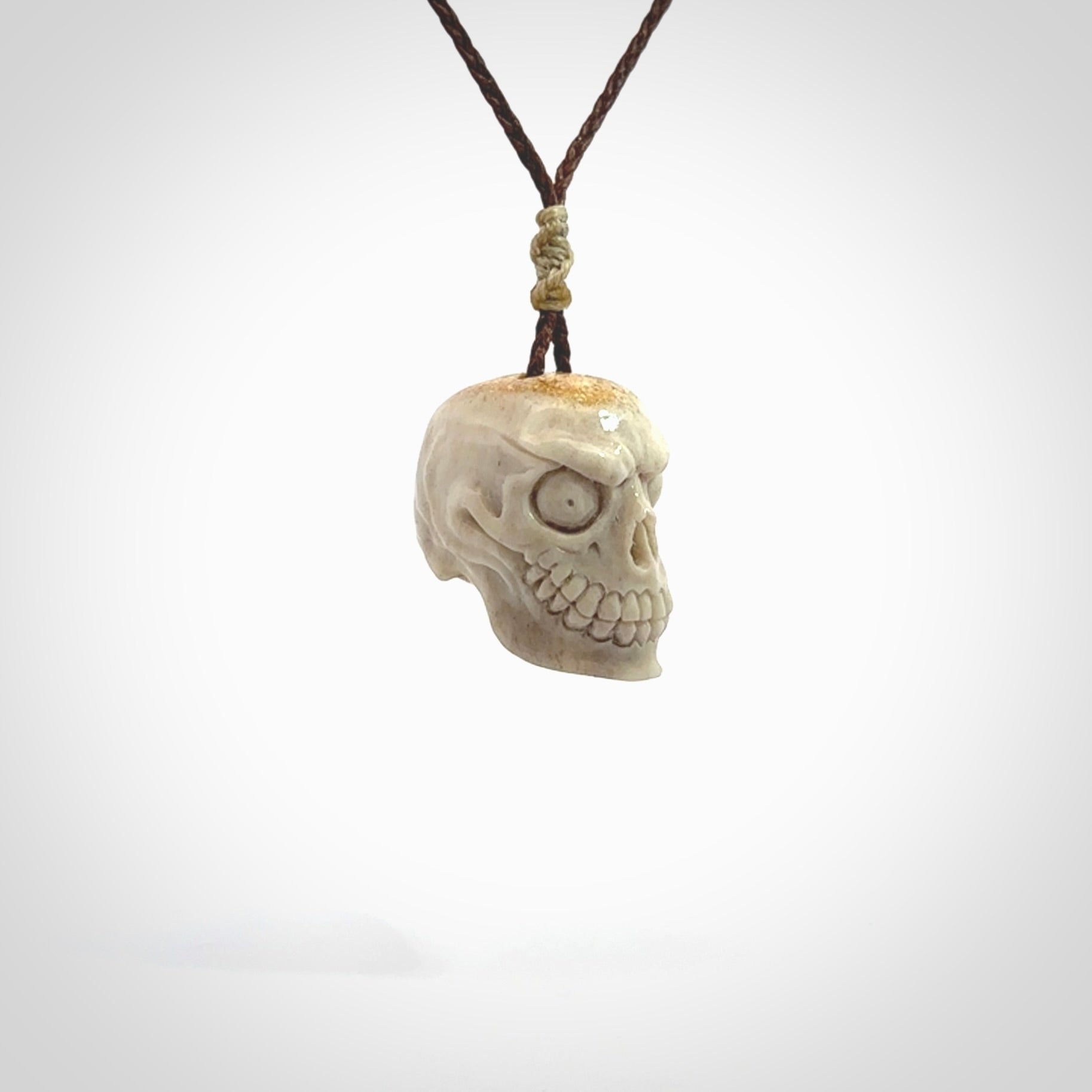 This picture shows a medium sized Deer Antler Bone monster skull pendant that we have hand carved. It is polished to a soft shine and is a very striking piece. The cord is a wapiti brown colour and has a small oat floret binding just above the pendant.