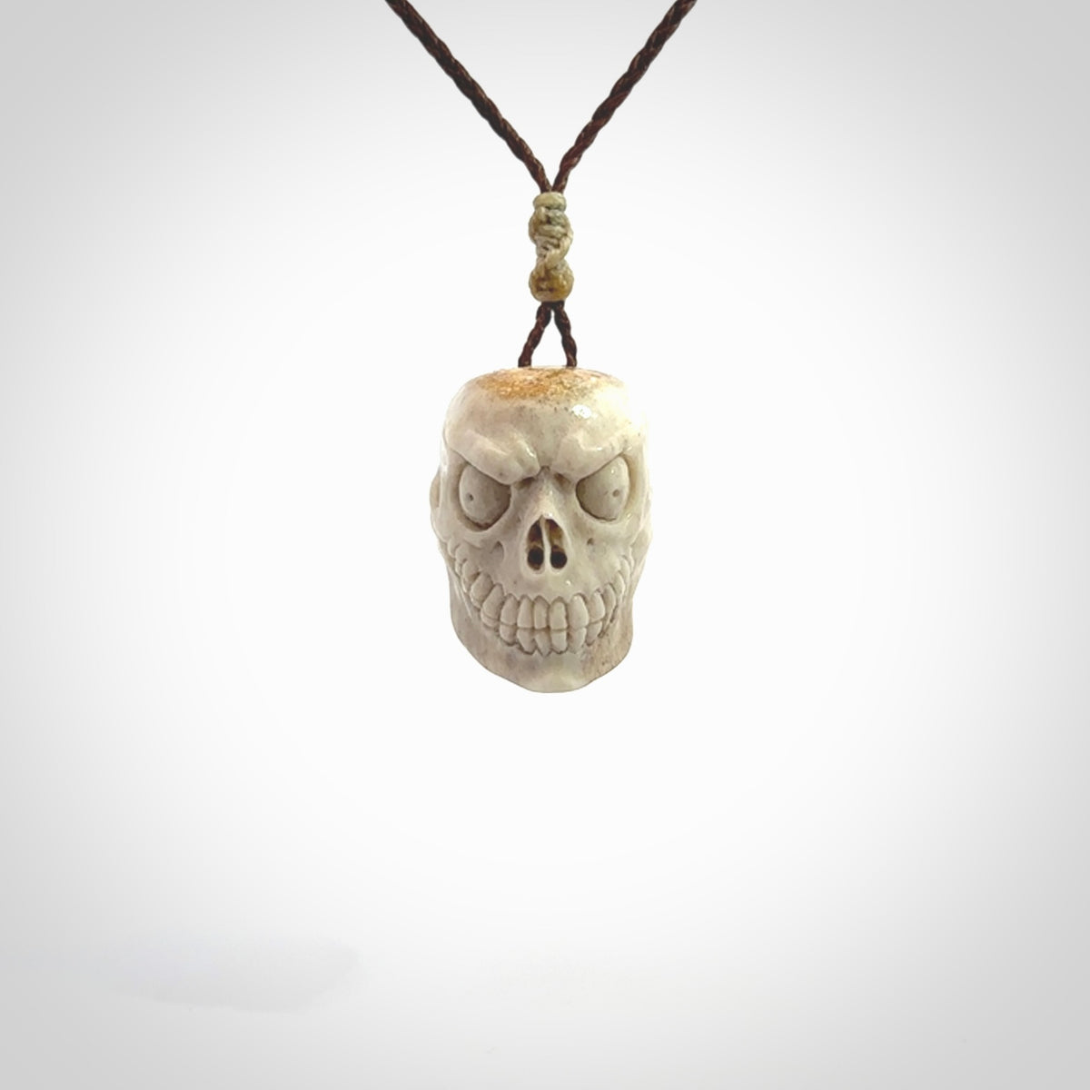 This picture shows a medium sized Deer Antler Bone monster skull pendant that we have hand carved. It is polished to a soft shine and is a very striking piece. The cord is a wapiti brown colour and has a small oat floret binding just above the pendant.