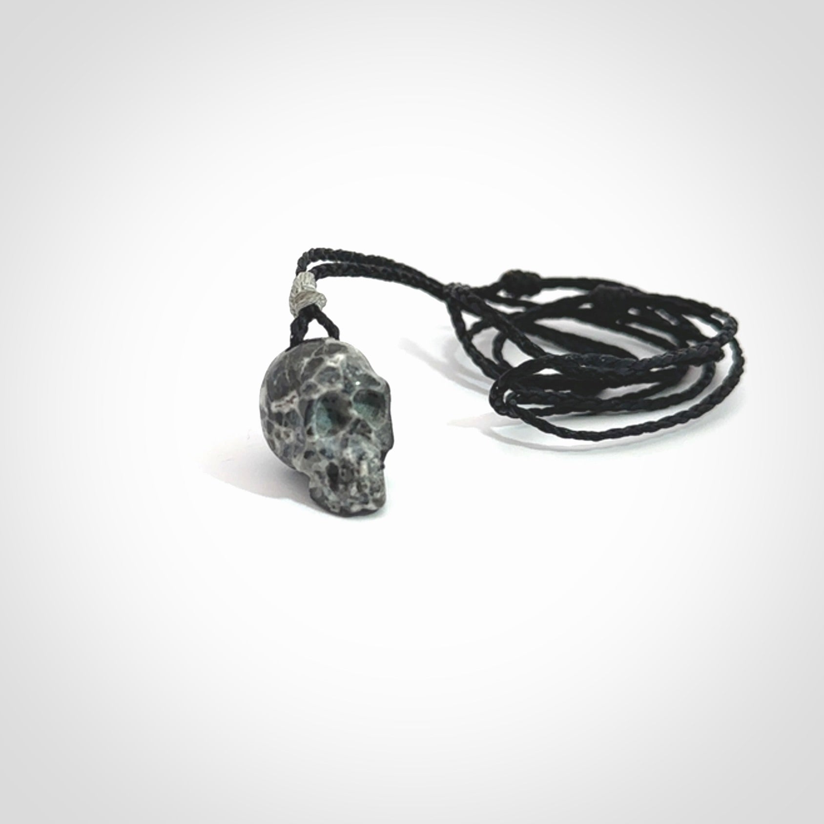 This picture shows a small sized Zebra Marble stone skull pendant that we have hand carved. It is polished to a soft shine and is a very striking piece. The cord is black and has a small grey floret binding just above the pendant.