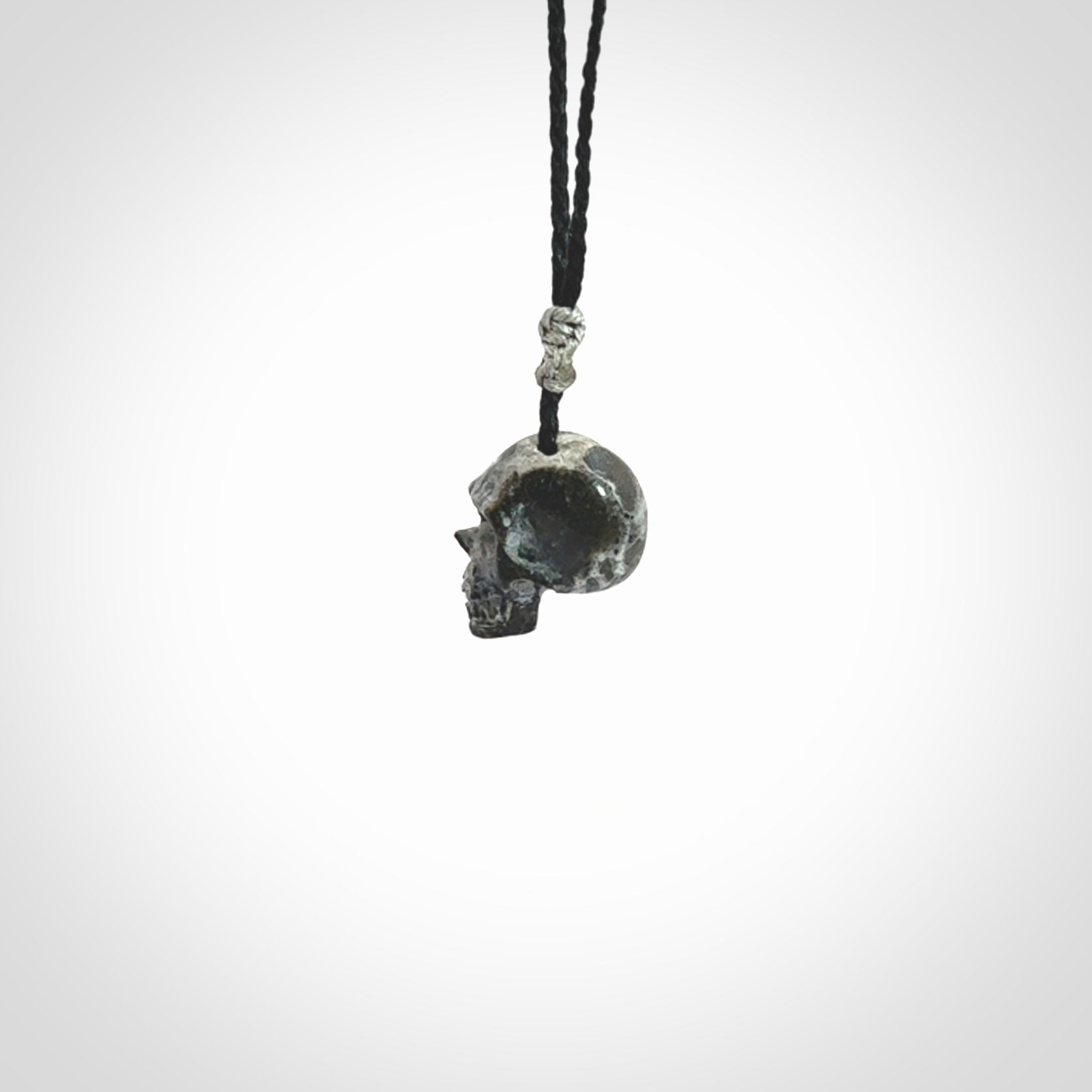 This picture shows a small sized Zebra Marble stone skull pendant that we have hand carved. It is polished to a soft shine and is a very striking piece. The cord is black and has a small grey floret binding just above the pendant.