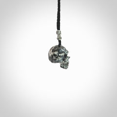 This picture shows a small sized Zebra Marble stone skull pendant that we have hand carved. It is polished to a soft shine and is a very striking piece. The cord is black and has a small grey floret binding just above the pendant.