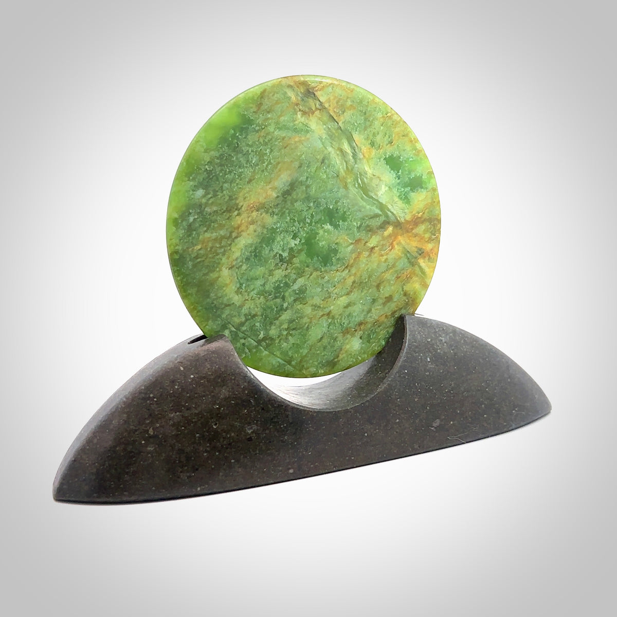 Hand carved New Zealand Flower Jade Disc with Greywacke stand sculpture. Hand carved here in New Zealand by Ric Moor. This is a 'one only' sculpture, a beautiful display piece. Small Jade disc sculpture for desk.