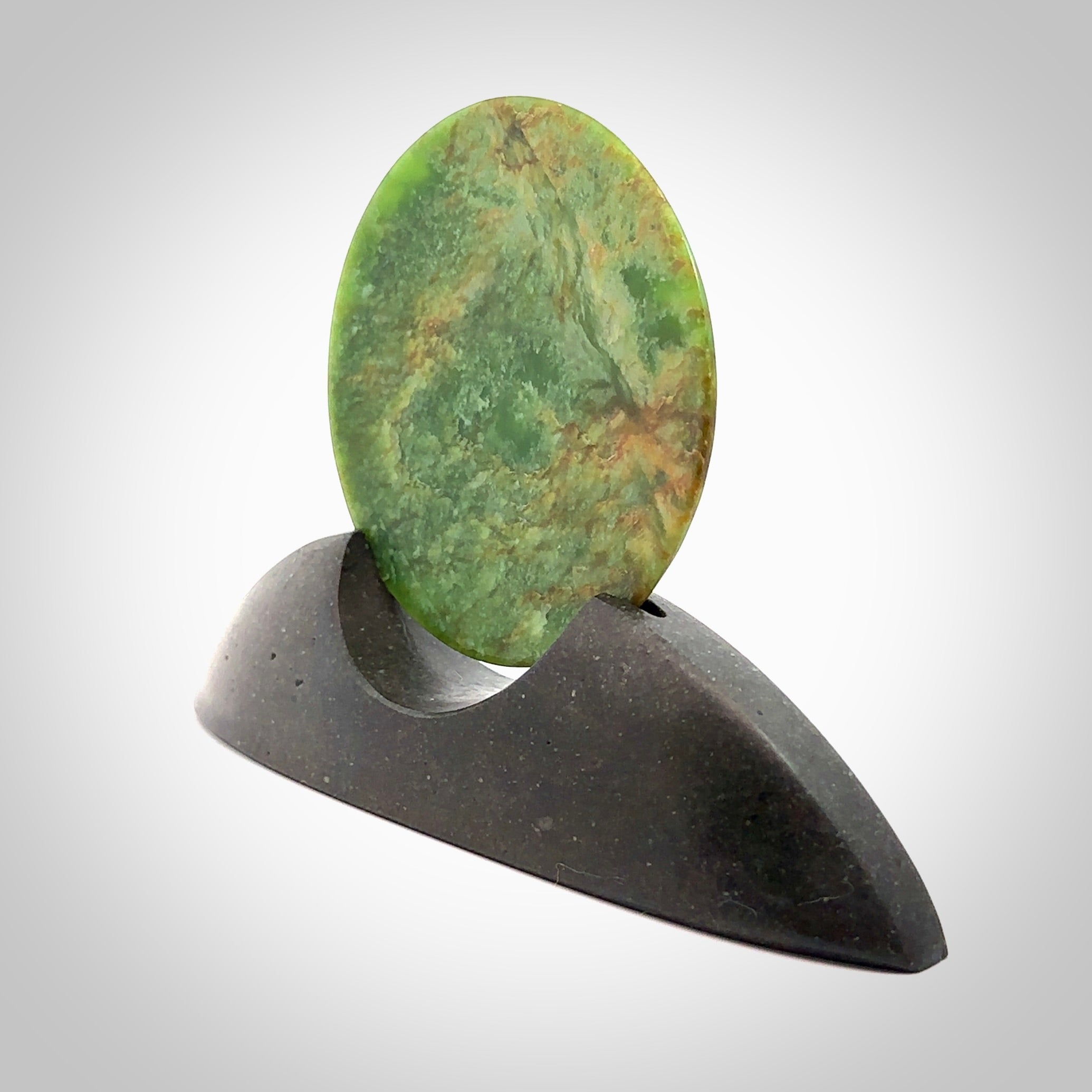 Hand carved New Zealand Flower Jade Disc with Greywacke stand sculpture. Hand carved here in New Zealand by Ric Moor. This is a 'one only' sculpture, a beautiful display piece. Small Jade disc sculpture for desk.