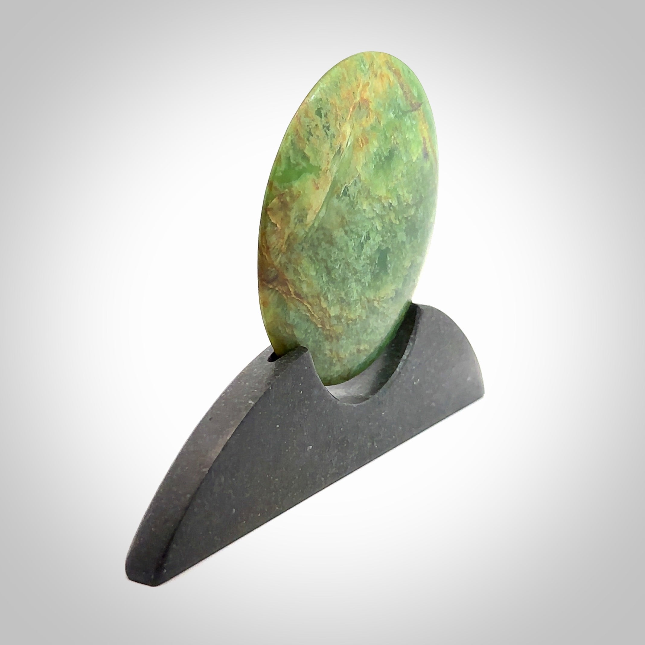 Hand carved New Zealand Flower Jade Disc with Greywacke stand sculpture. Hand carved here in New Zealand by Ric Moor. This is a 'one only' sculpture, a beautiful display piece. Small Jade disc sculpture for desk.