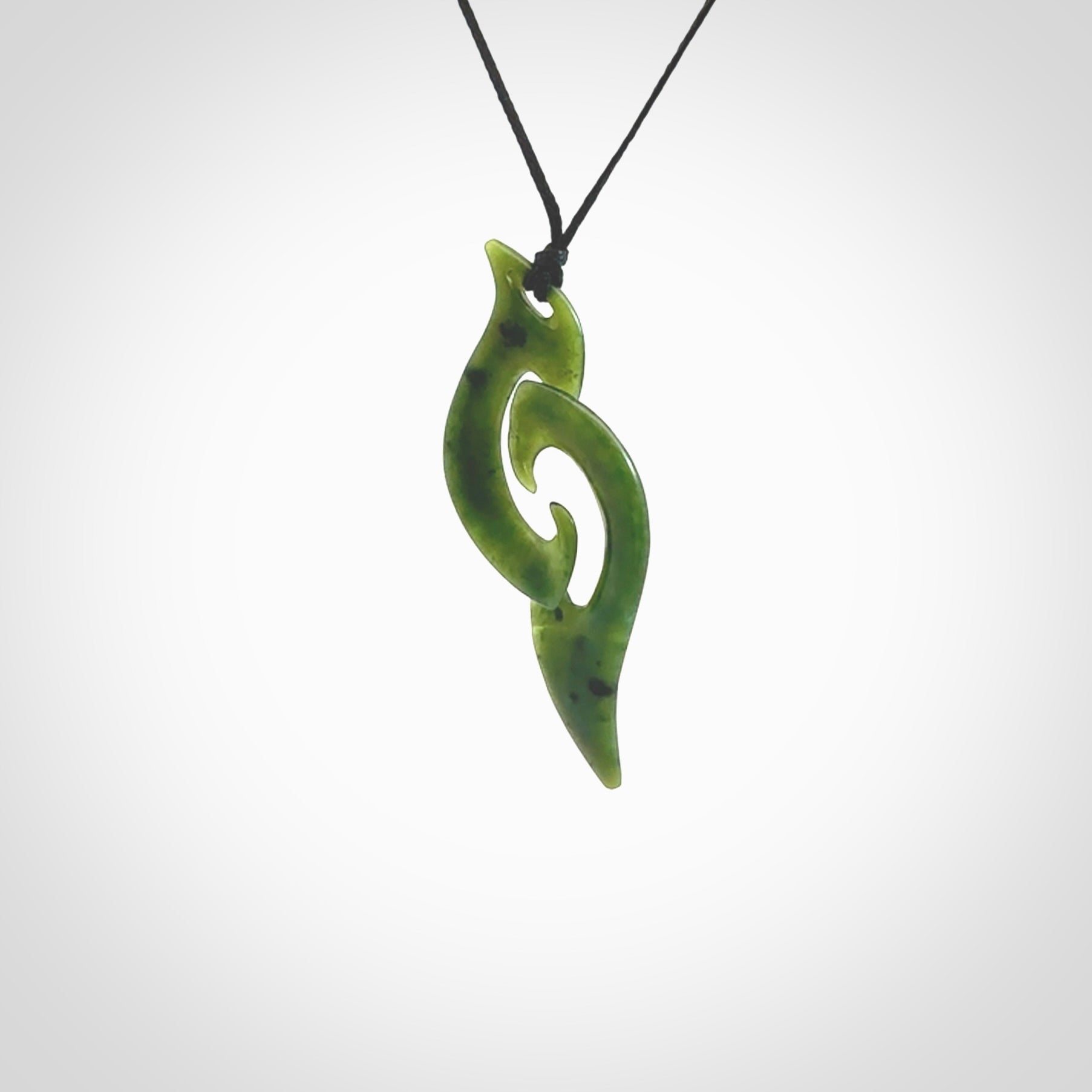 This photo shows a contemporary koru pendant carved from New Zealand Jade. The artist, Shaun Gardiner, has carved this beautifully. We provide this piece with an adjustable black cord. This is a fantastic work of art, we have one only.