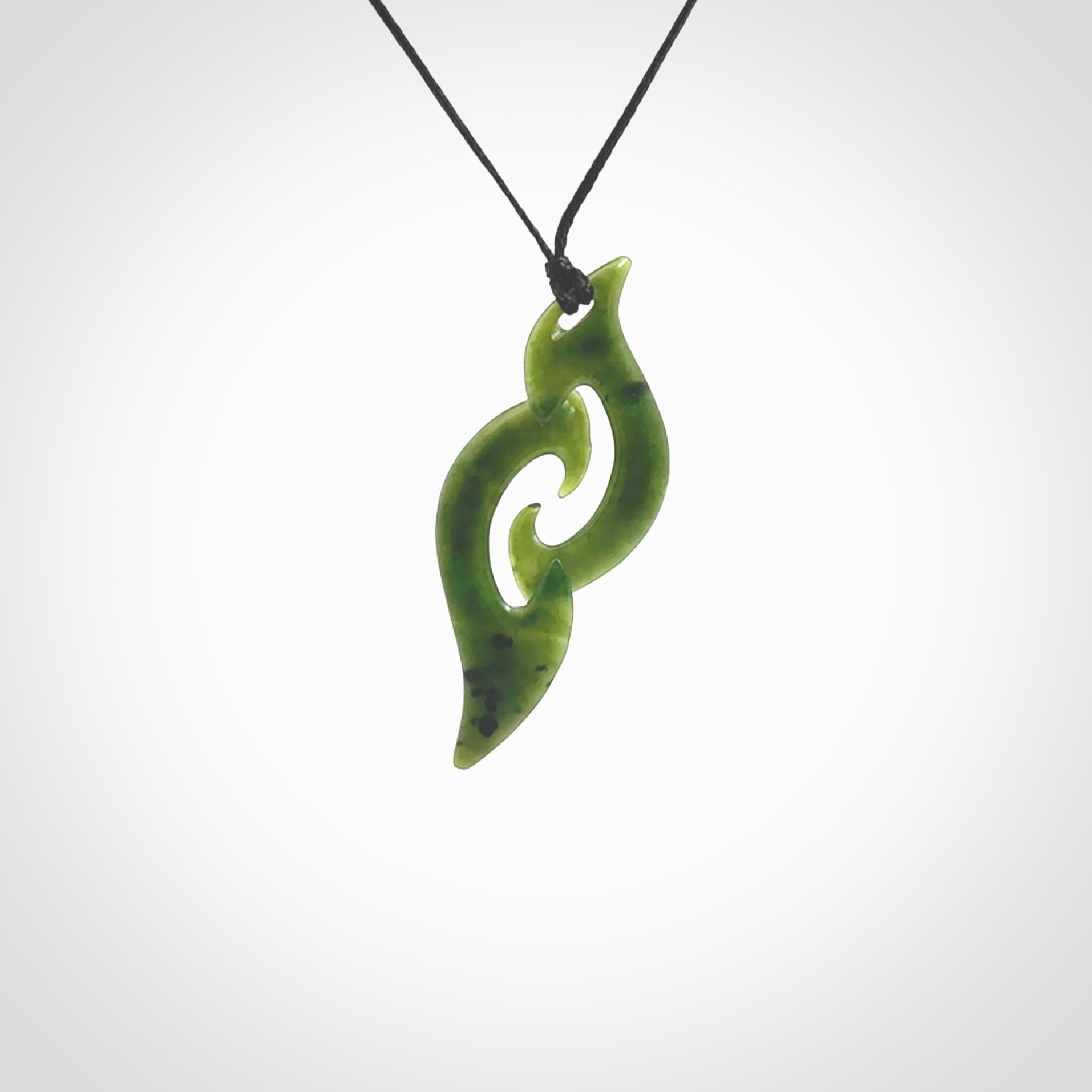 This photo shows a contemporary koru pendant carved from New Zealand Jade. The artist, Shaun Gardiner, has carved this beautifully. We provide this piece with an adjustable black cord. This is a fantastic work of art, we have one only.