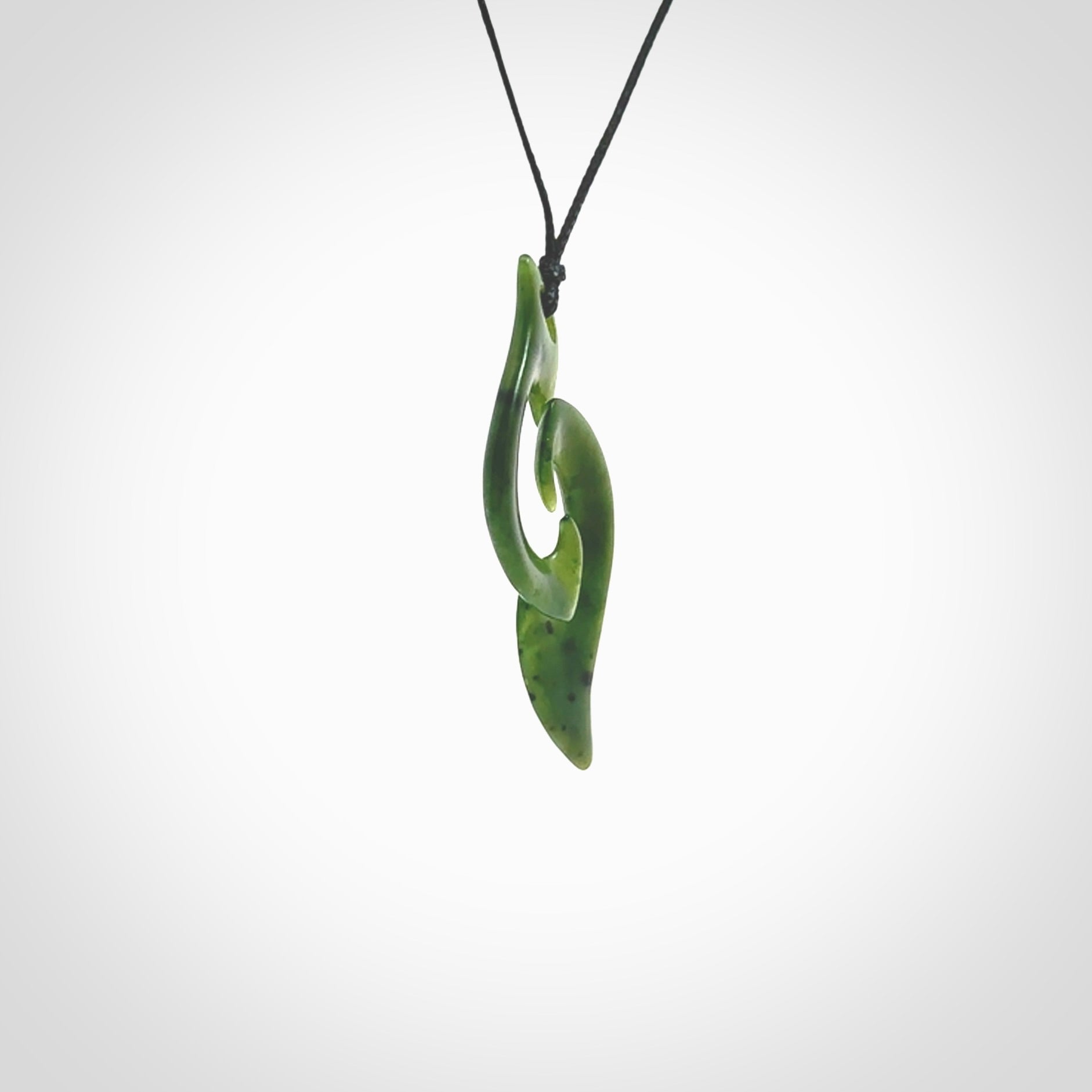 This photo shows a contemporary koru pendant carved from New Zealand Jade. The artist, Shaun Gardiner, has carved this beautifully. We provide this piece with an adjustable black cord. This is a fantastic work of art, we have one only.