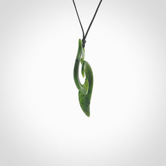 This photo shows a contemporary koru pendant carved from New Zealand Jade. The artist, Shaun Gardiner, has carved this beautifully. We provide this piece with an adjustable black cord. This is a fantastic work of art, we have one only.