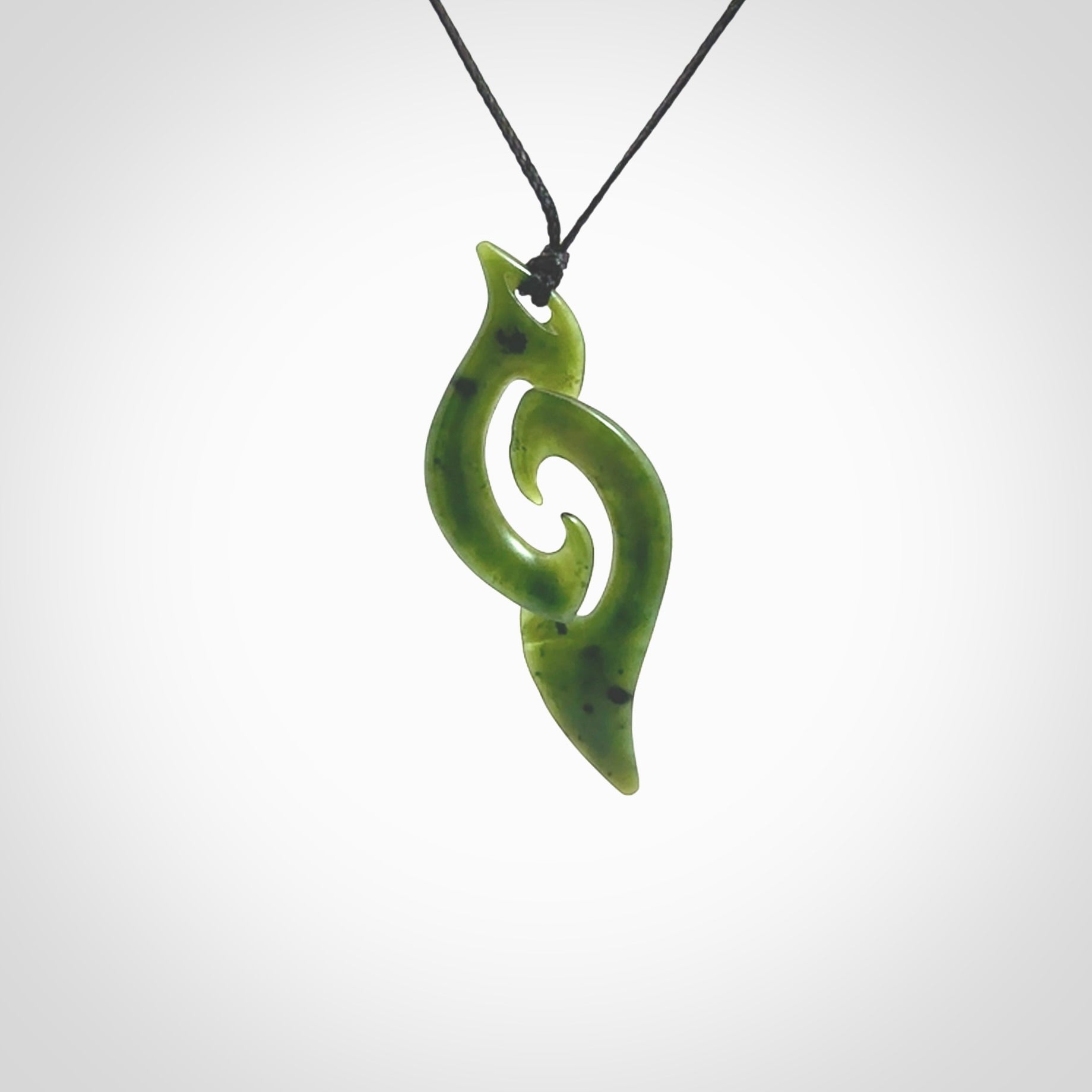 This photo shows a contemporary koru pendant carved from New Zealand Jade. The artist, Shaun Gardiner, has carved this beautifully. We provide this piece with an adjustable black cord. This is a fantastic work of art, we have one only.