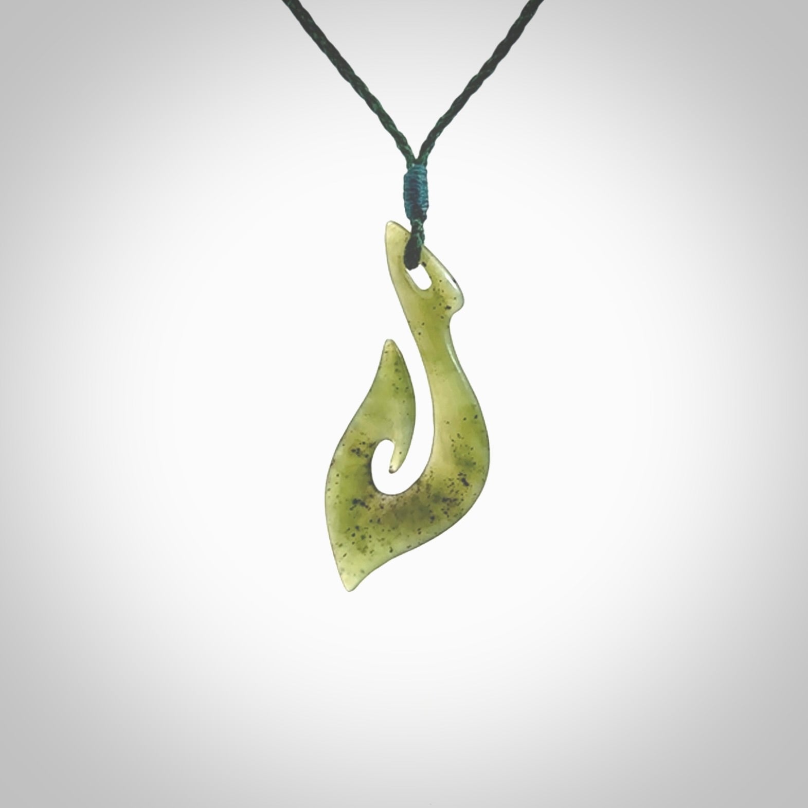 This photo shows a matau pendant carved from New Zealand Kawakawa Jade. The artist, Shaun Gardiner, has carved this beautifully. We provide this piece with an adjustable green coloured cord. This is a fantastic work of art, we have one only.