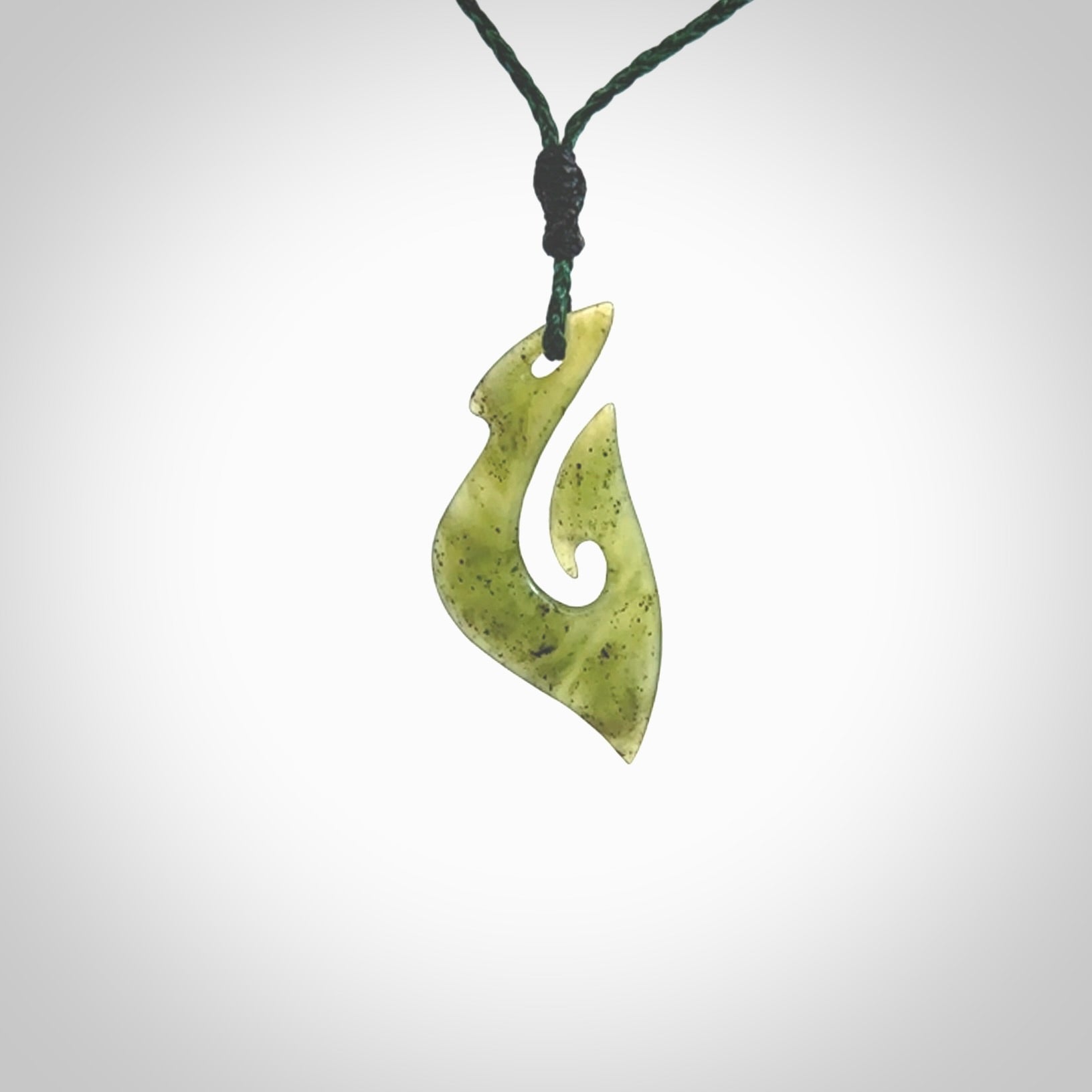 This photo shows a matau pendant carved from New Zealand Kawakawa Jade. The artist, Shaun Gardiner, has carved this beautifully. We provide this piece with an adjustable green coloured cord. This is a fantastic work of art, we have one only.