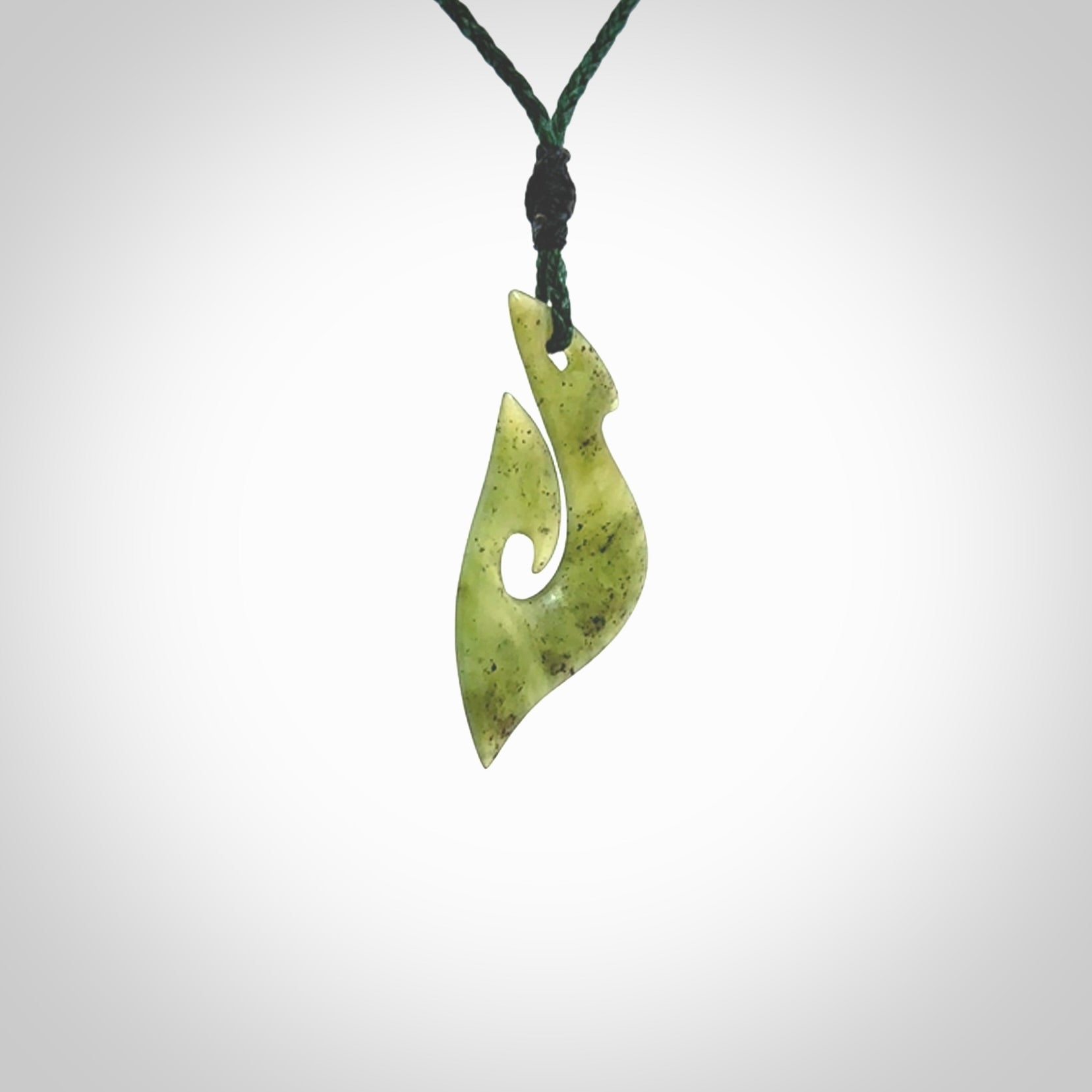 This photo shows a matau pendant carved from New Zealand Kawakawa Jade. The artist, Shaun Gardiner, has carved this beautifully. We provide this piece with an adjustable green coloured cord. This is a fantastic work of art, we have one only.