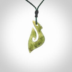 This photo shows a matau pendant carved from New Zealand Kawakawa Jade. The artist, Shaun Gardiner, has carved this beautifully. We provide this piece with an adjustable green coloured cord. This is a fantastic work of art, we have one only.