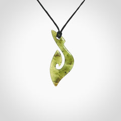 This photo shows a matau pendant carved from New Zealand Jade. The artist, Shaun Gardiner, has carved this beautifully. We provide this piece with an adjustable black coloured cord. This is a fantastic work of art, we have one only.