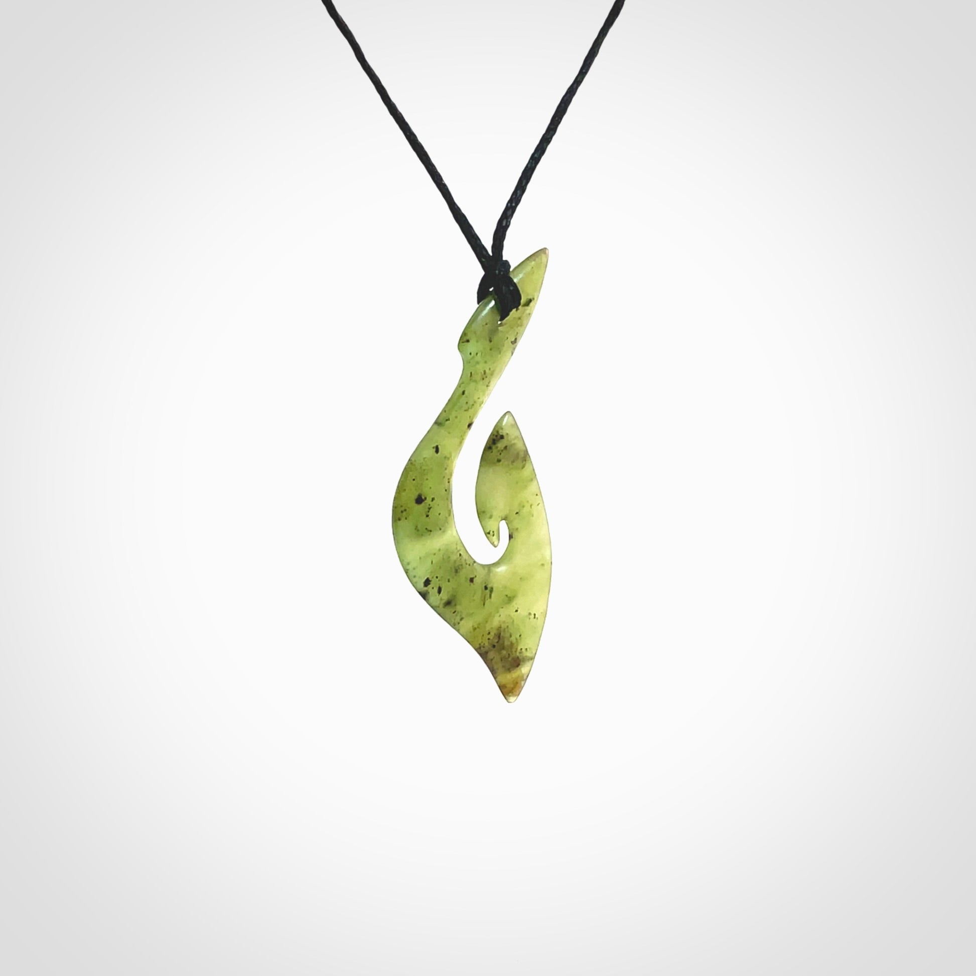 This photo shows a matau pendant carved from New Zealand Jade. The artist, Shaun Gardiner, has carved this beautifully. We provide this piece with an adjustable black coloured cord. This is a fantastic work of art, we have one only.