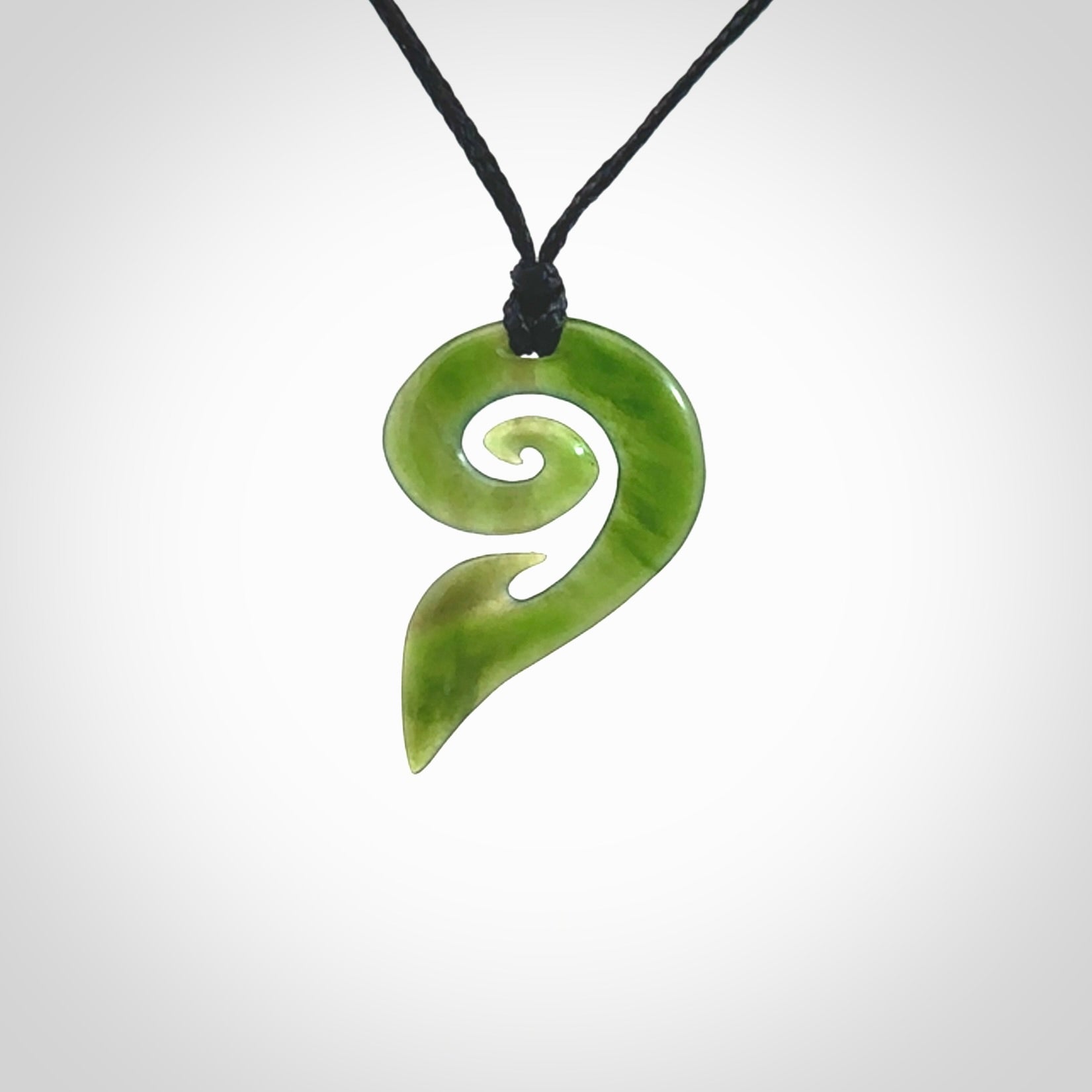 This photo shows a koru pendant carved from New Zealand Jade. The artist, Shaun Gardiner, has carved this beautifully. We provide this piece with an adjustable black cord. This is a fantastic work of art, we have one only.