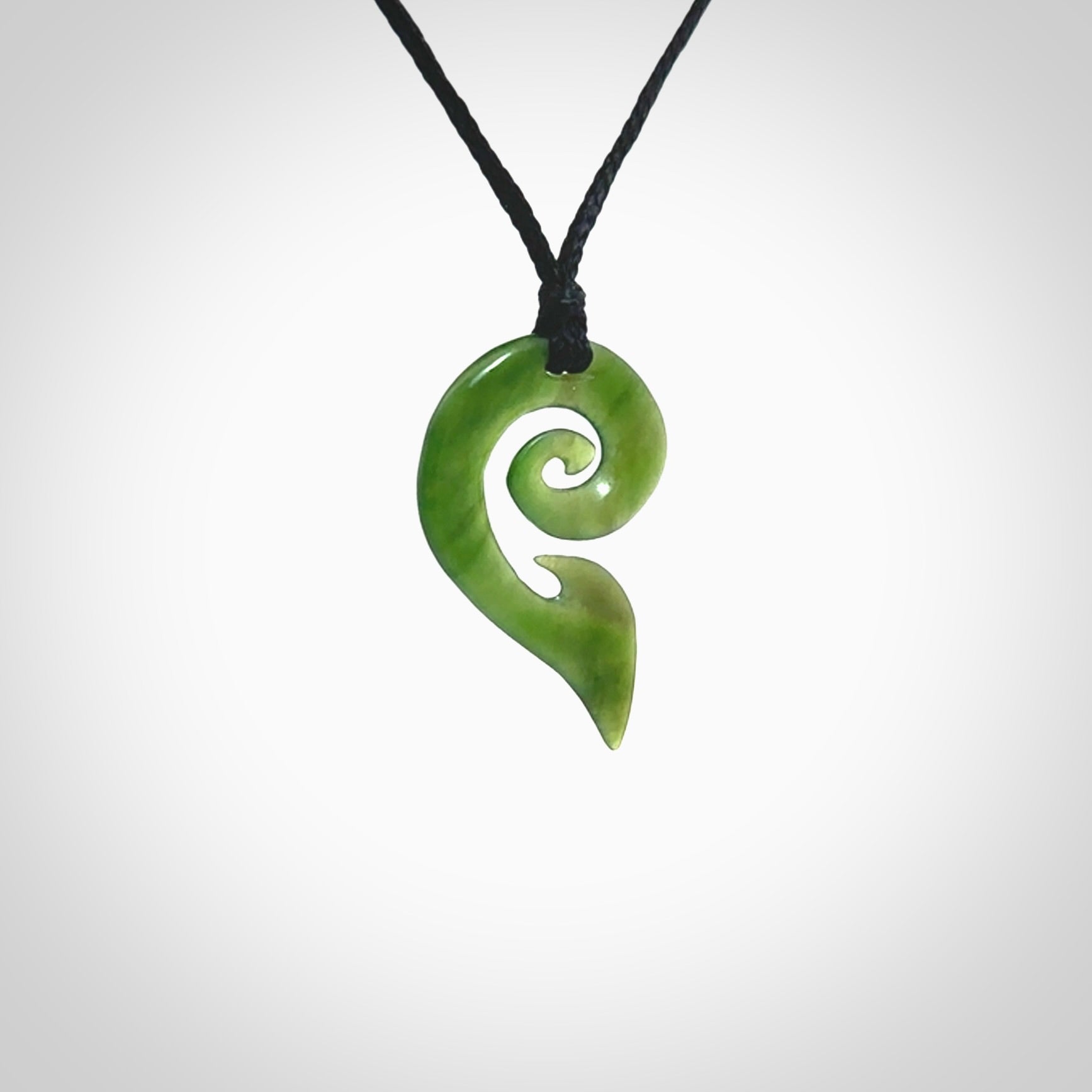 This photo shows a koru pendant carved from New Zealand Jade. The artist, Shaun Gardiner, has carved this beautifully. We provide this piece with an adjustable black cord. This is a fantastic work of art, we have one only.