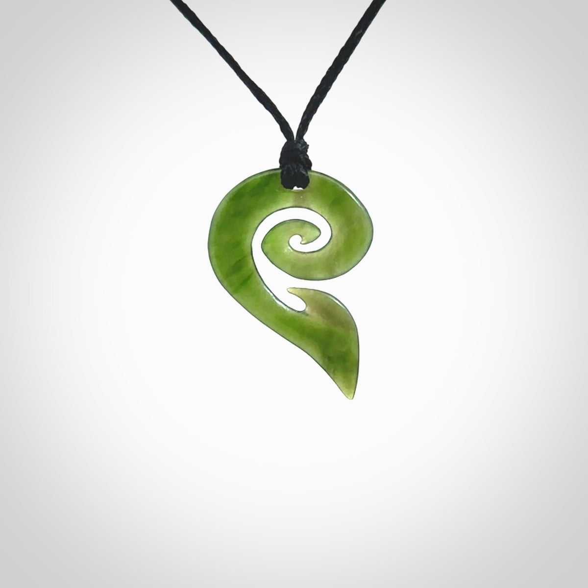 This photo shows a koru pendant carved from New Zealand Jade. The artist, Shaun Gardiner, has carved this beautifully. We provide this piece with an adjustable black cord. This is a fantastic work of art, we have one only.