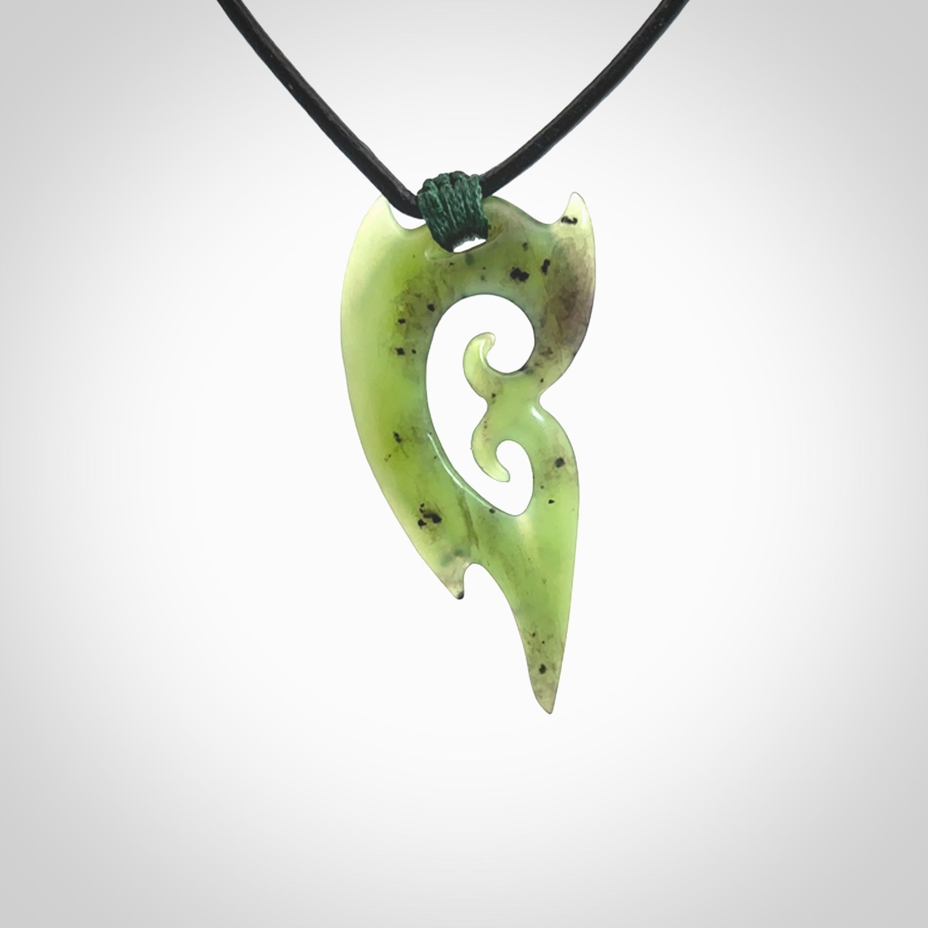 This photo shows a large contemporary double koru pendant carved from New Zealand Jade. The artist, Shaun Gardiner, has carved this beautifully. We provide this piece with a fixed length black leather cord. This is a fantastic work of art, we have one only.