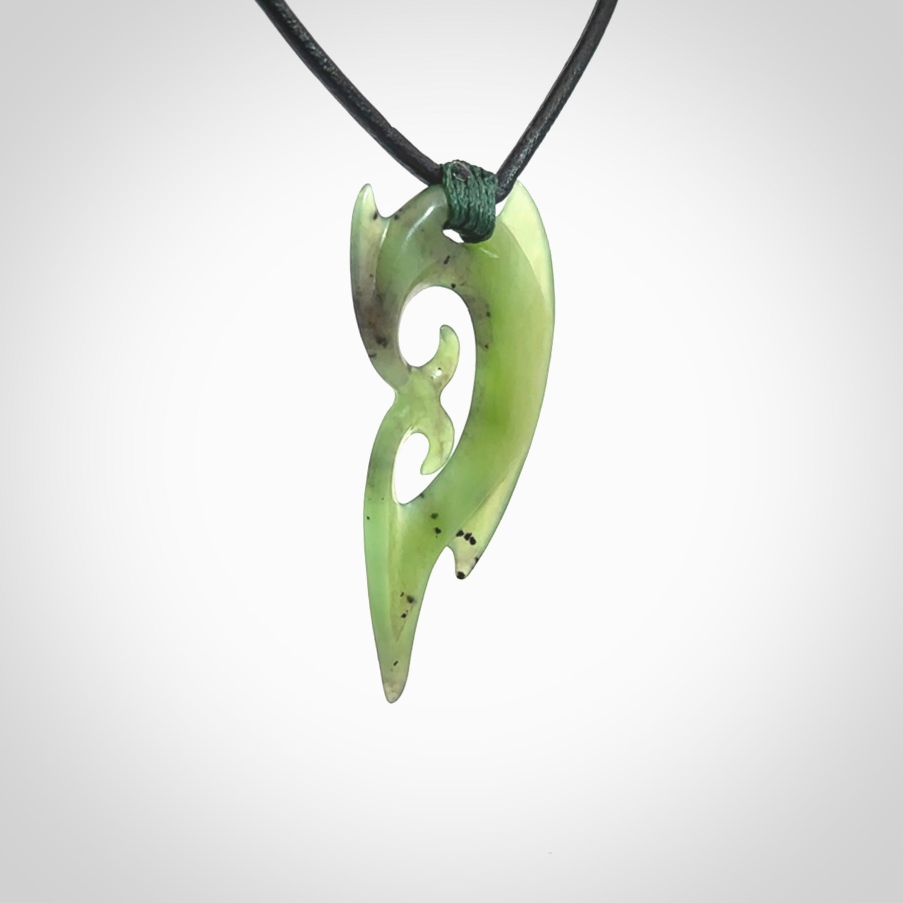 This photo shows a large contemporary double koru pendant carved from New Zealand Jade. The artist, Shaun Gardiner, has carved this beautifully. We provide this piece with a fixed length black leather cord. This is a fantastic work of art, we have one only.