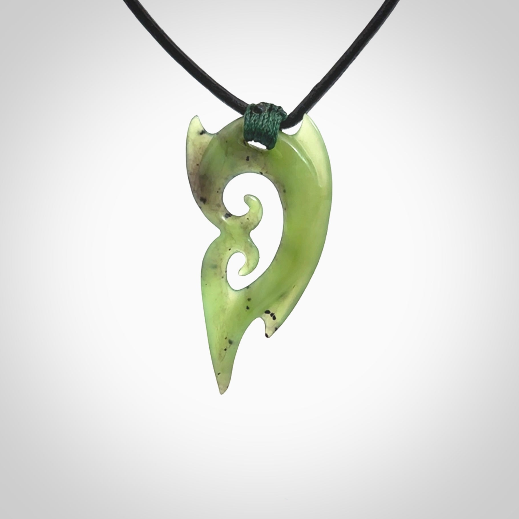 This photo shows a large contemporary double koru pendant carved from New Zealand Jade. The artist, Shaun Gardiner, has carved this beautifully. We provide this piece with a fixed length black leather cord. This is a fantastic work of art, we have one only.