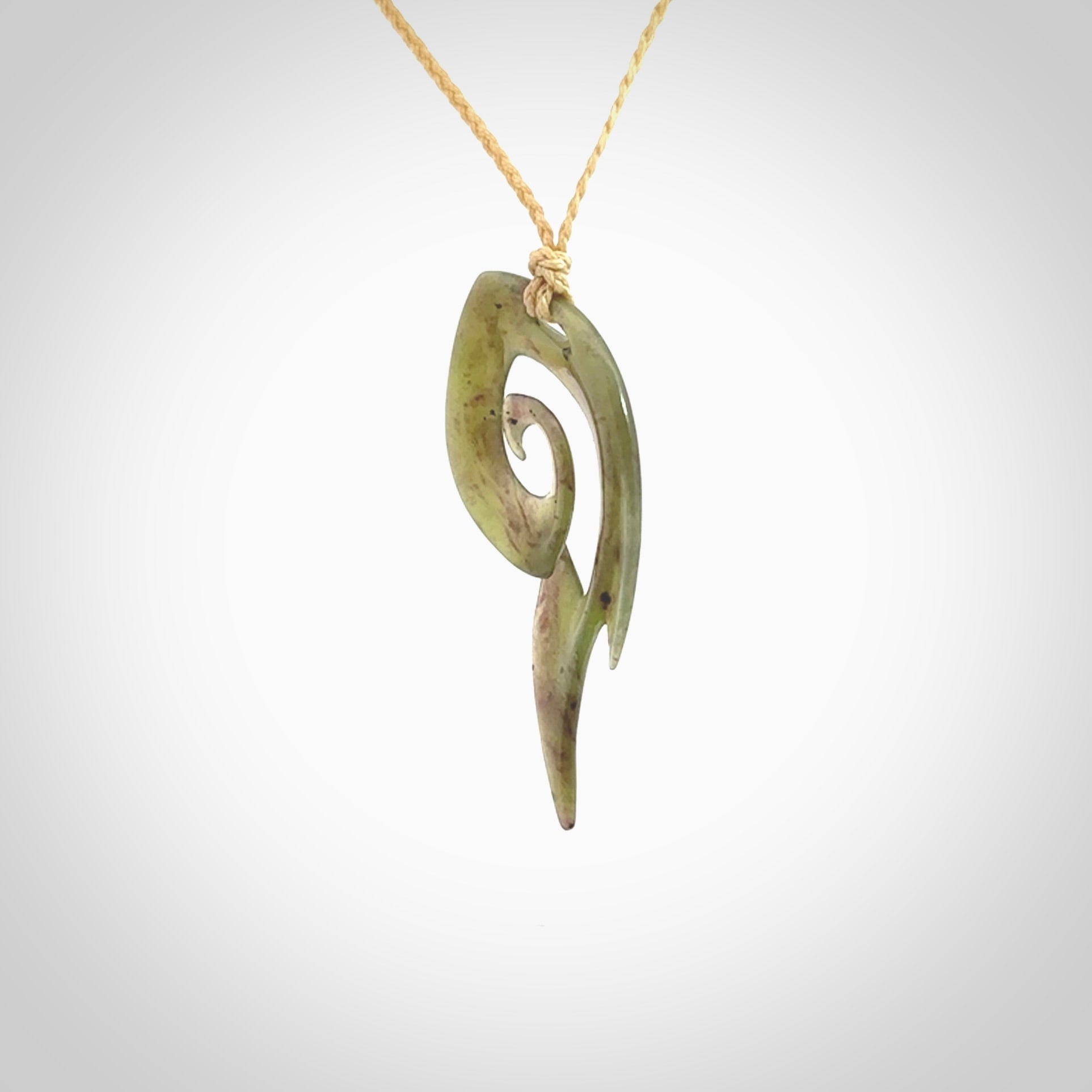 This photo shows a contemporary koru pendant carved from New Zealand Jade. The artist, Shaun Gardiner, has carved this beautifully. We provide this piece with an adjustable oat coloured cord. This is a fantastic work of art, we have one only.